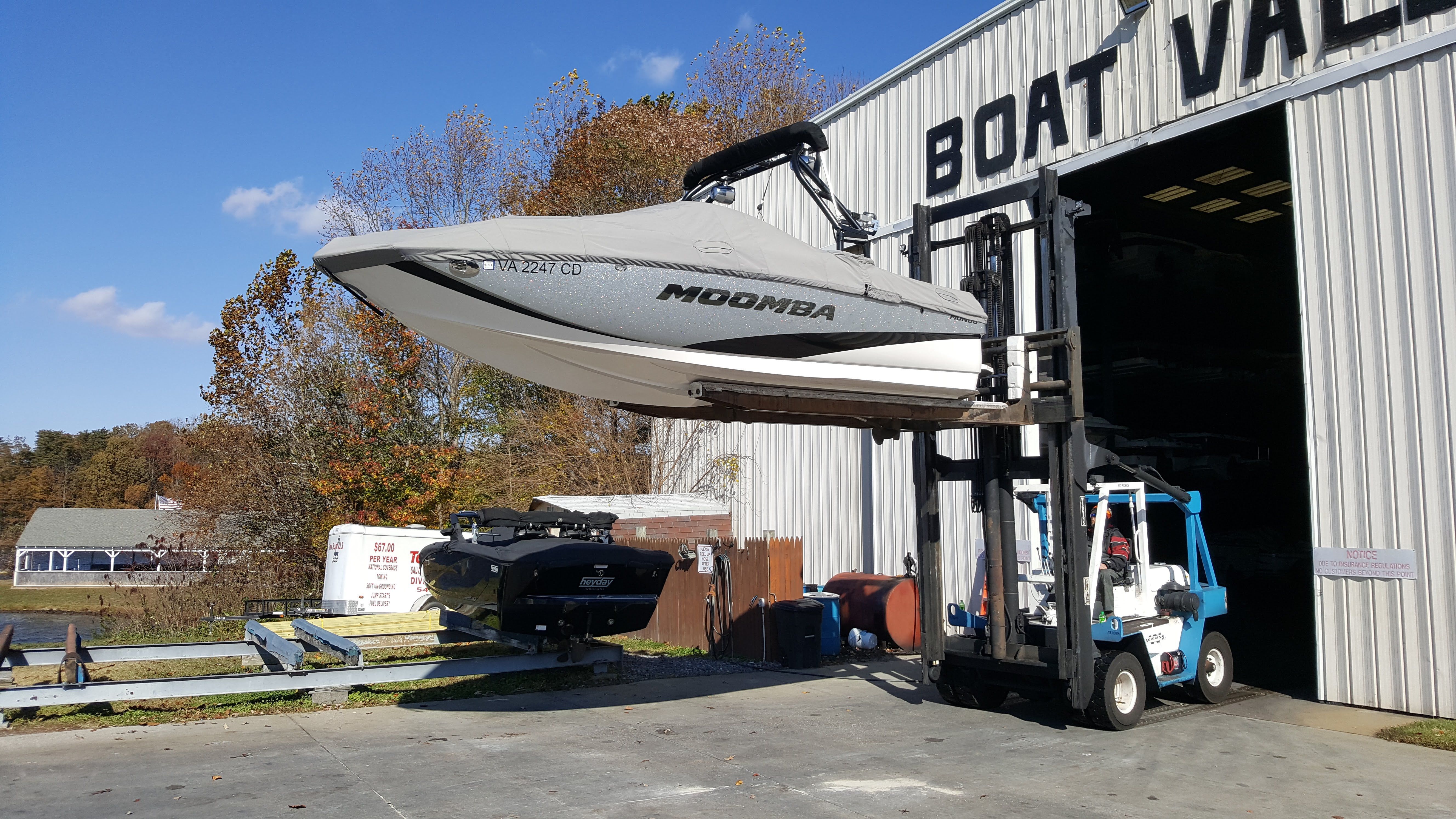 A 2016 Moomba Mondo being lifted by a forklift from a boat storage facility.