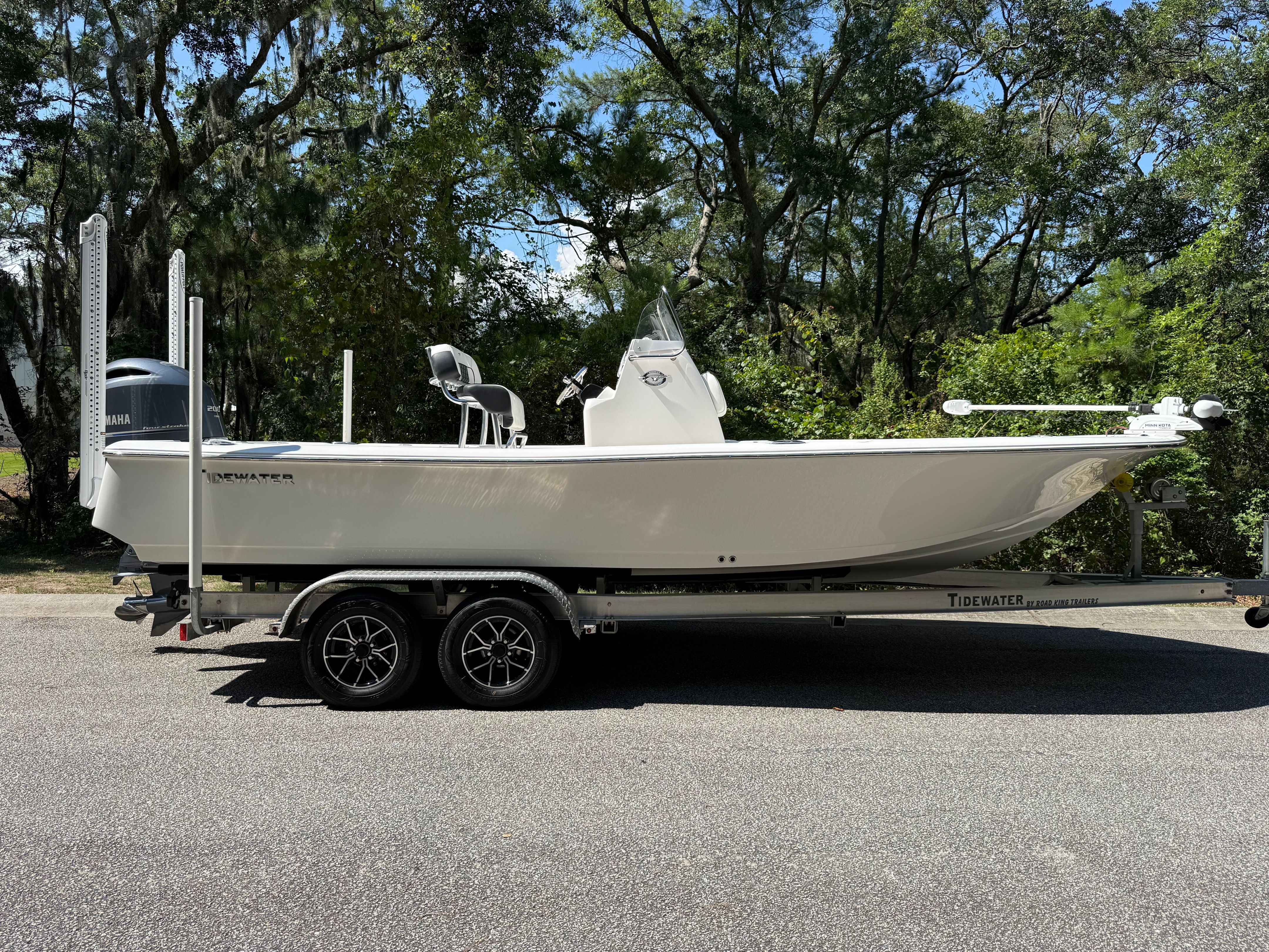 A 2023 Tidewater 2210 Carolina Bay boat on a trailer, surrounded by trees.