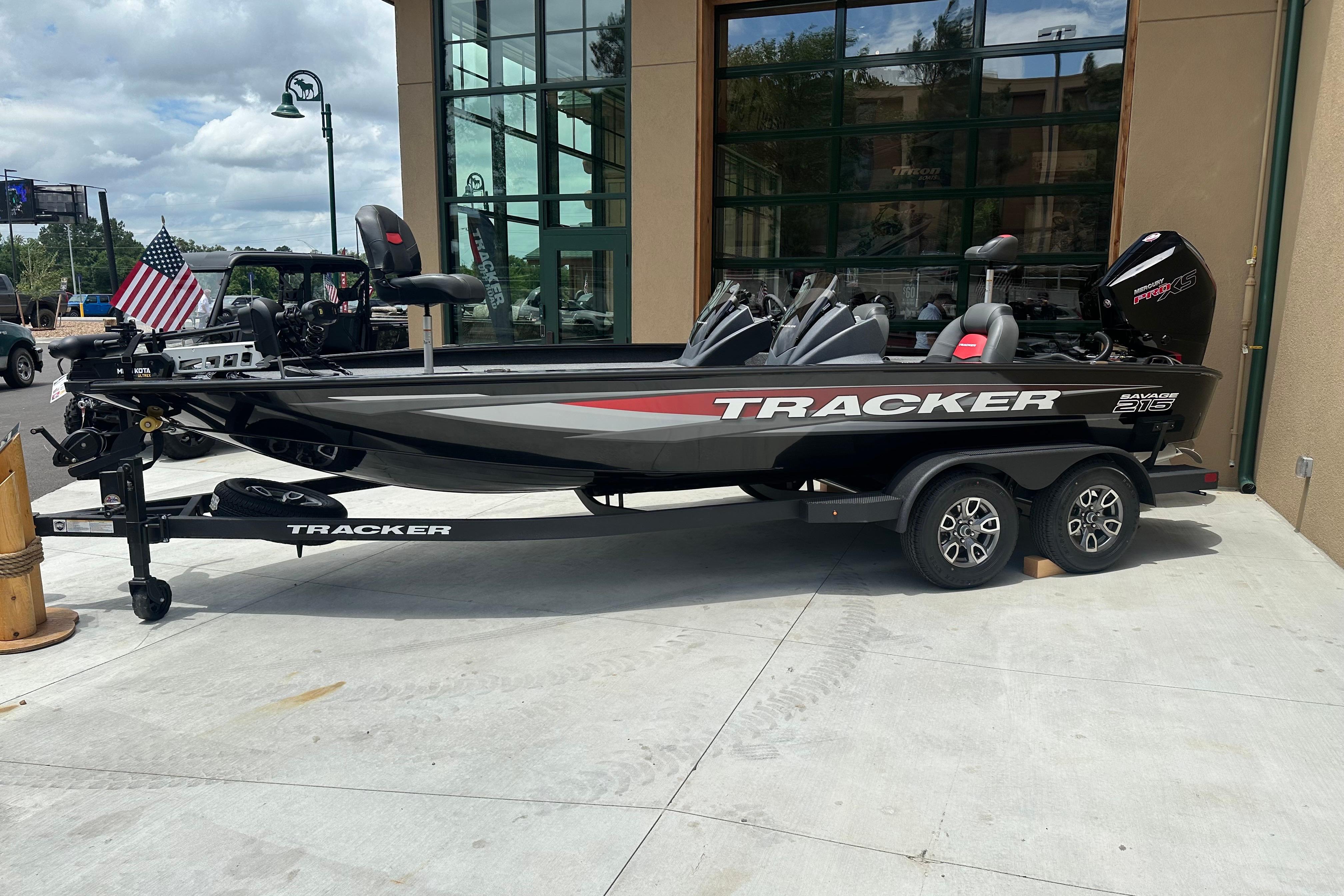 2025 Tracker Savage 215 boat on trailer, parked outside a building.