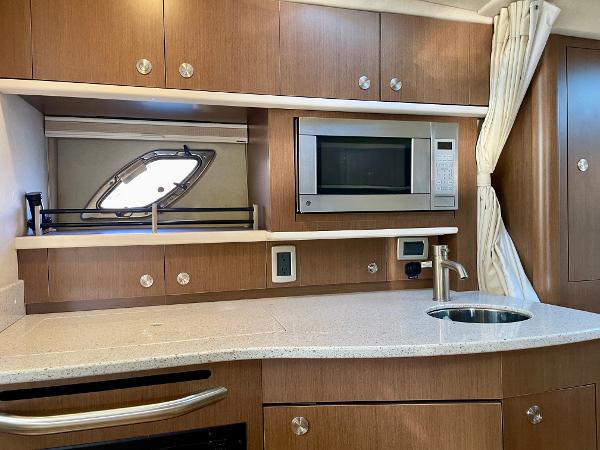 2014 Sea Ray 330 Sundancer kitchen with microwave, sink, and wooden cabinetry.