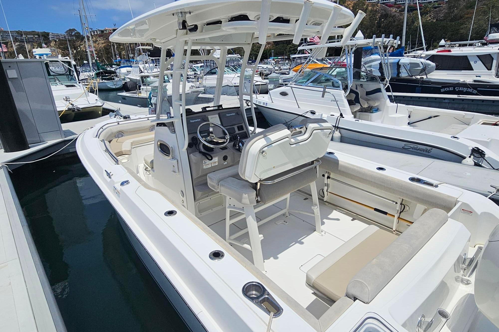 2017 Boston Whaler 230 Outrage boat docked in a marina, showcasing sleek design and spacious seating.