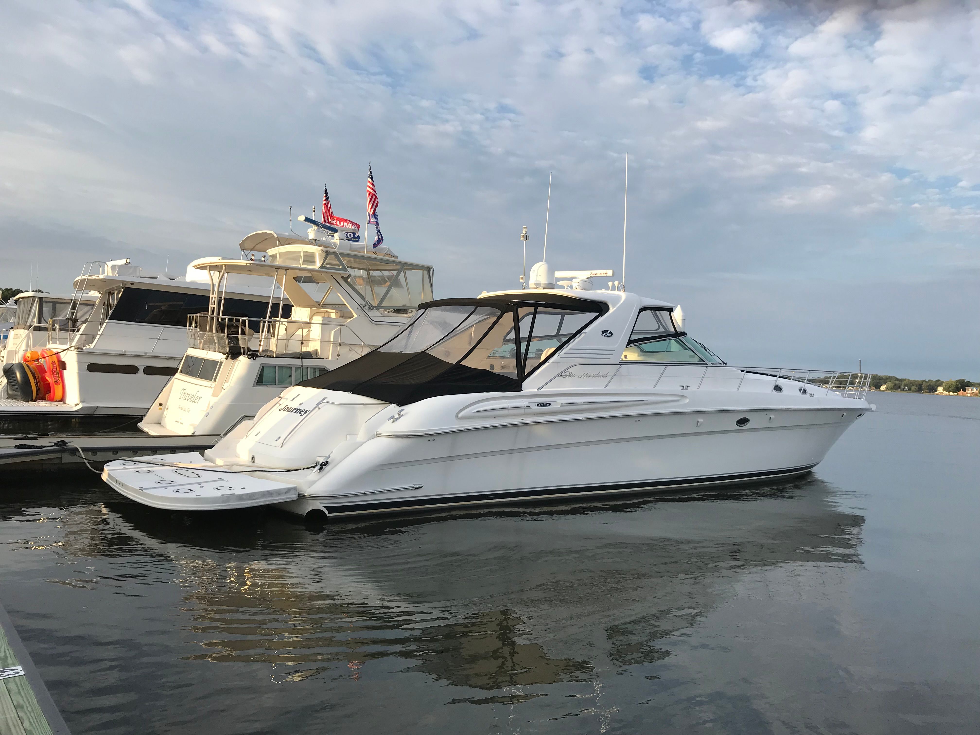 A white 2003 Sea Ray S600 Sunsport is docked on calm water beside other boats.