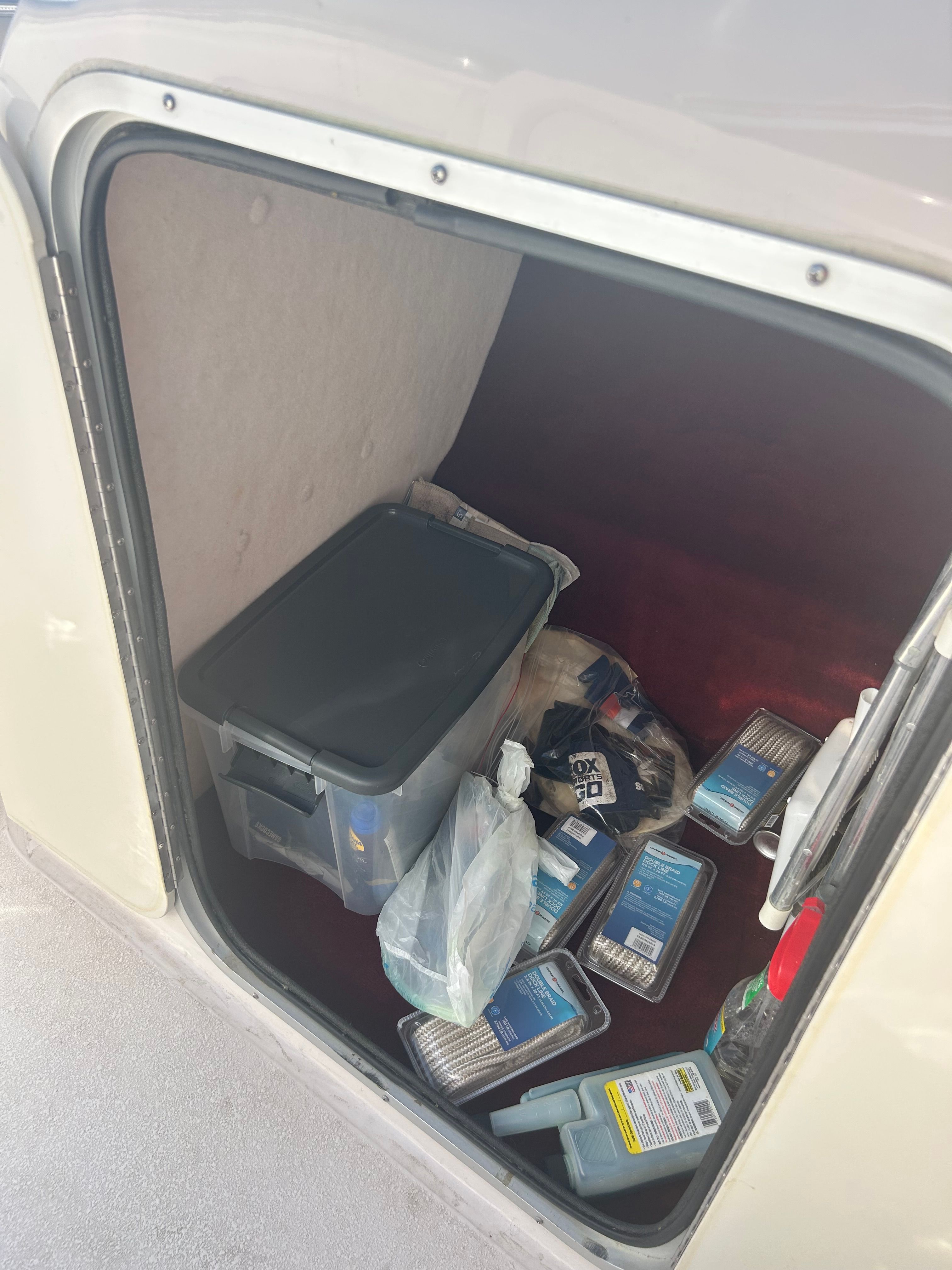 A storage compartment on a 1995 Chaparral 2330 boat with various items inside.