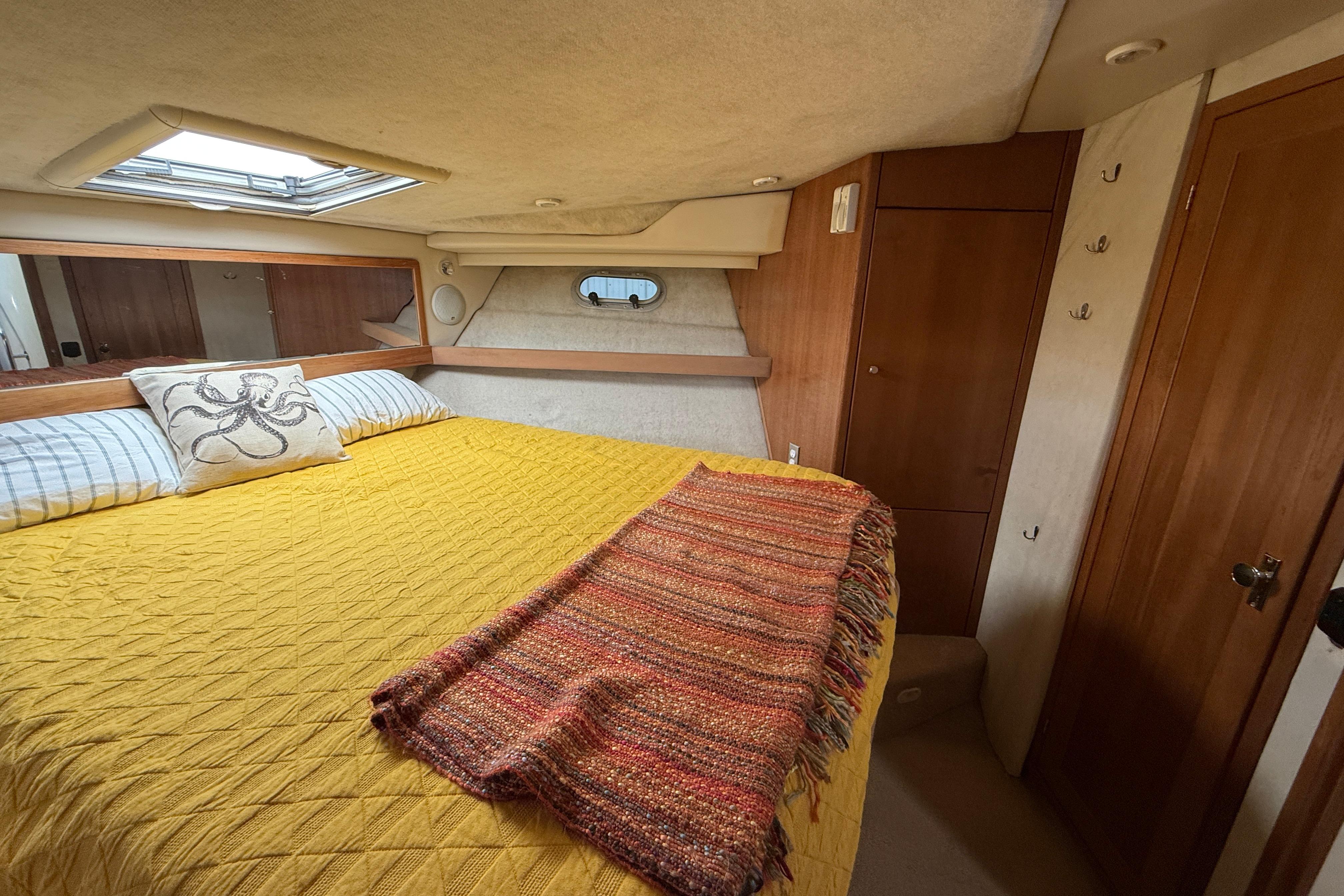 Cozy bedroom in 1997 Bayliner 3988 Command Bridge Motoryacht with yellow bedding and skylight.