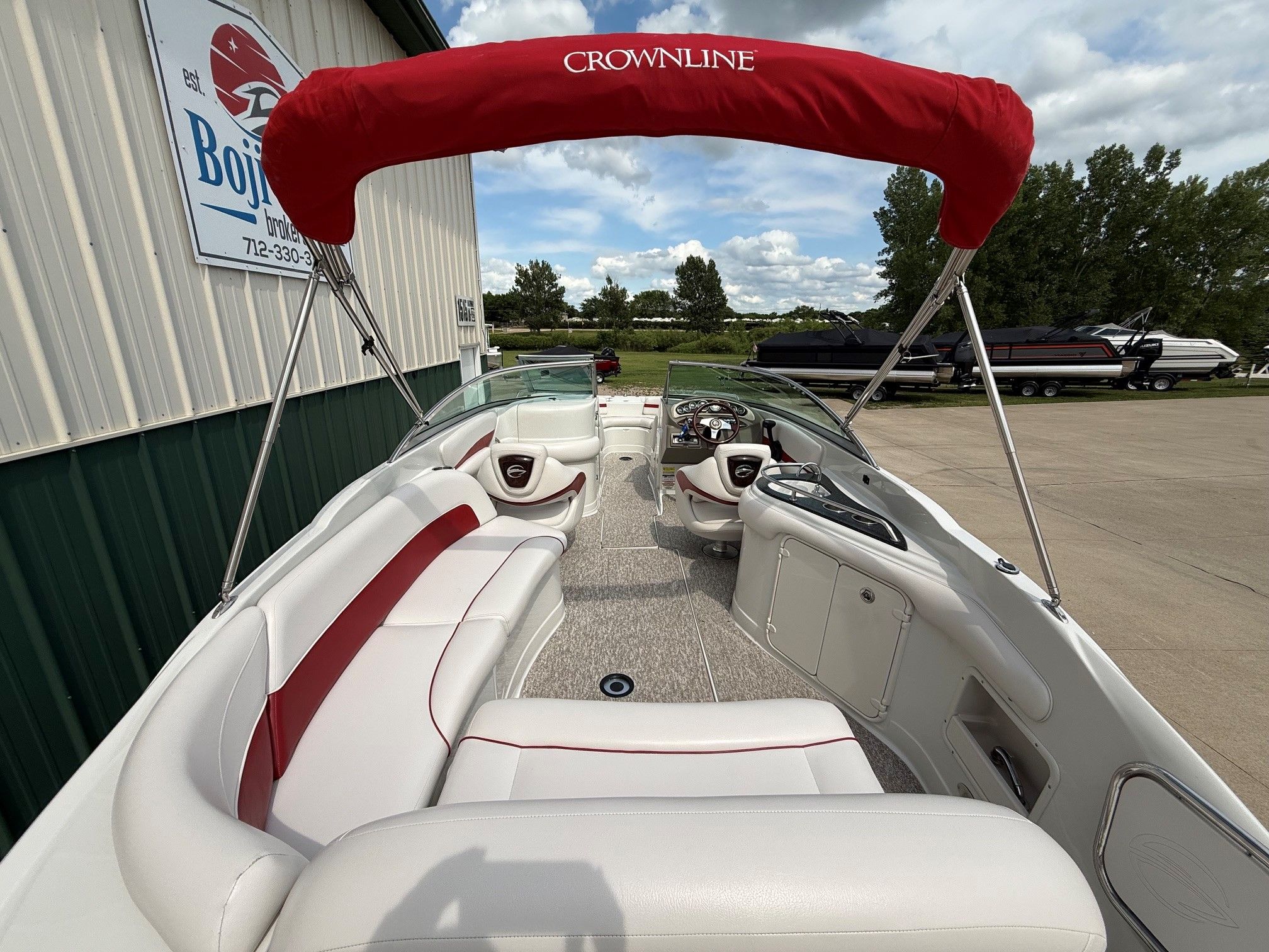 The image shows a 2012 Crownline 252 EX boat with a red sunshade.
