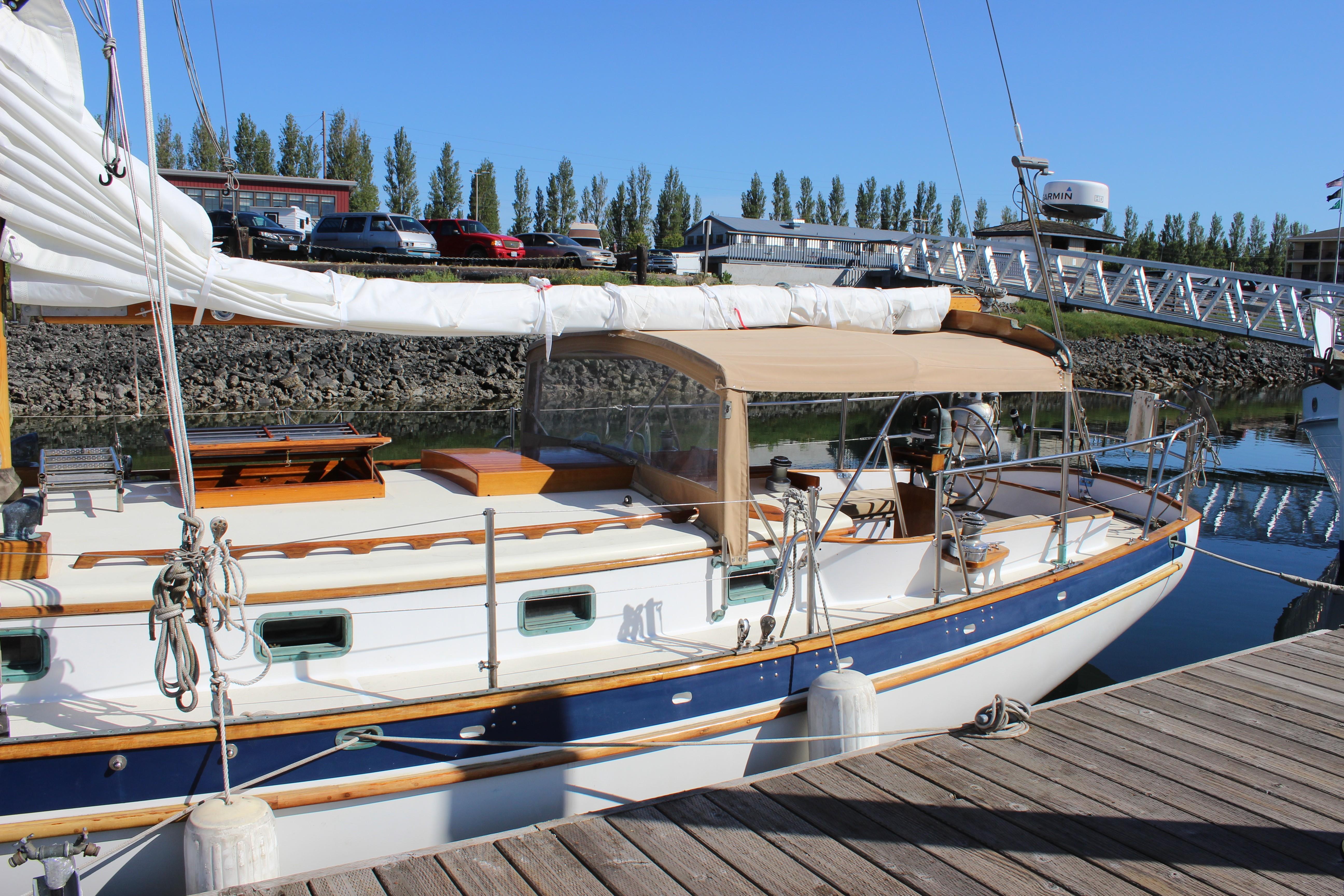 Sailboat docked at marina, Cape George 38, 1988 model, with tan canopy and white hull.