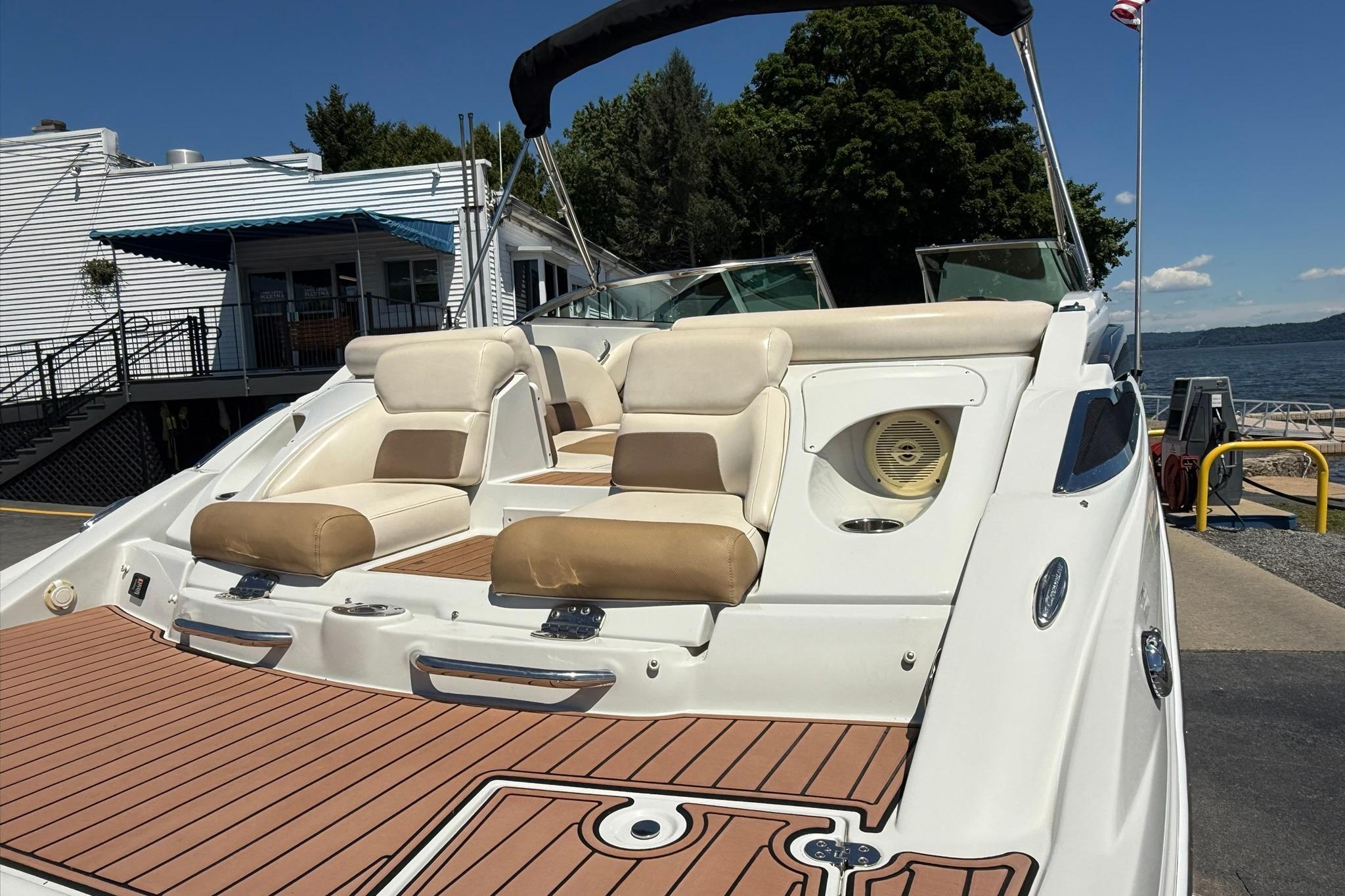 2016 Crownline 255 SS boat with beige seating, docked near a waterfront building.