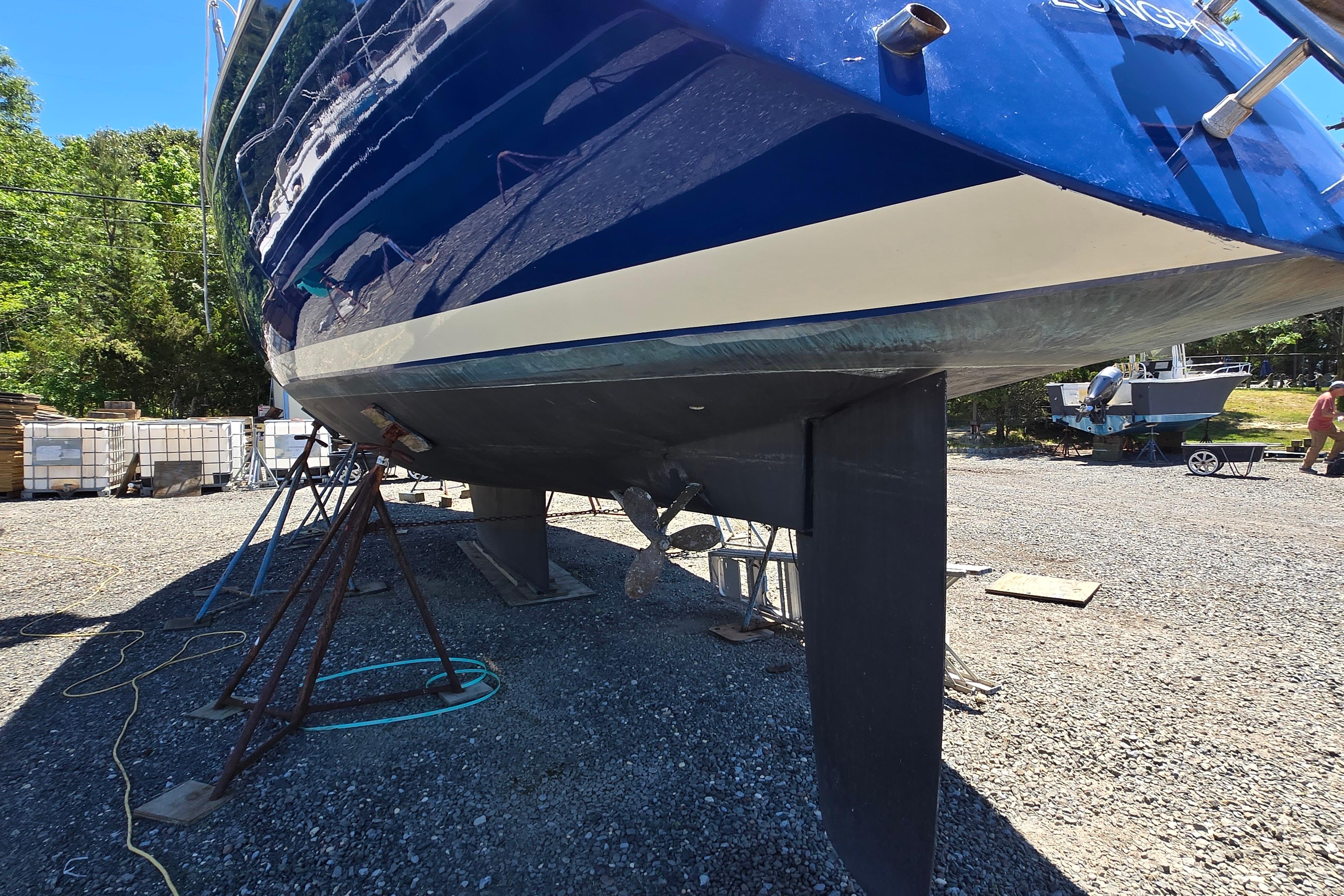 1988 Sabre 38 sailboat on dry dock, blue hull, keel visible, sunny day.