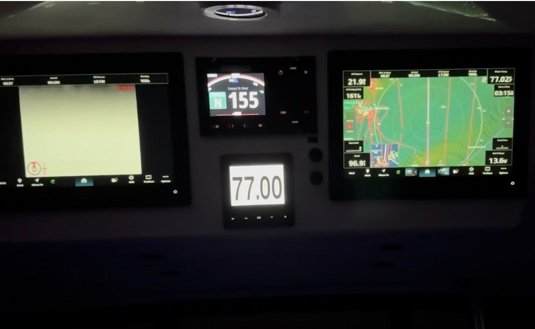 The image shows a boat's dashboard with multiple screens and instruments.