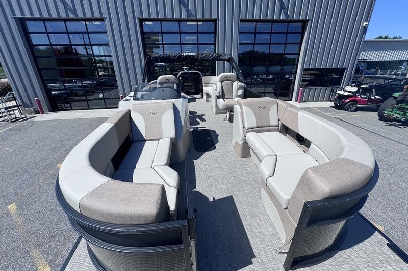 2027 Manitou Aurora 23 RF SHP pontoon boat with spacious seating, parked outside a building.