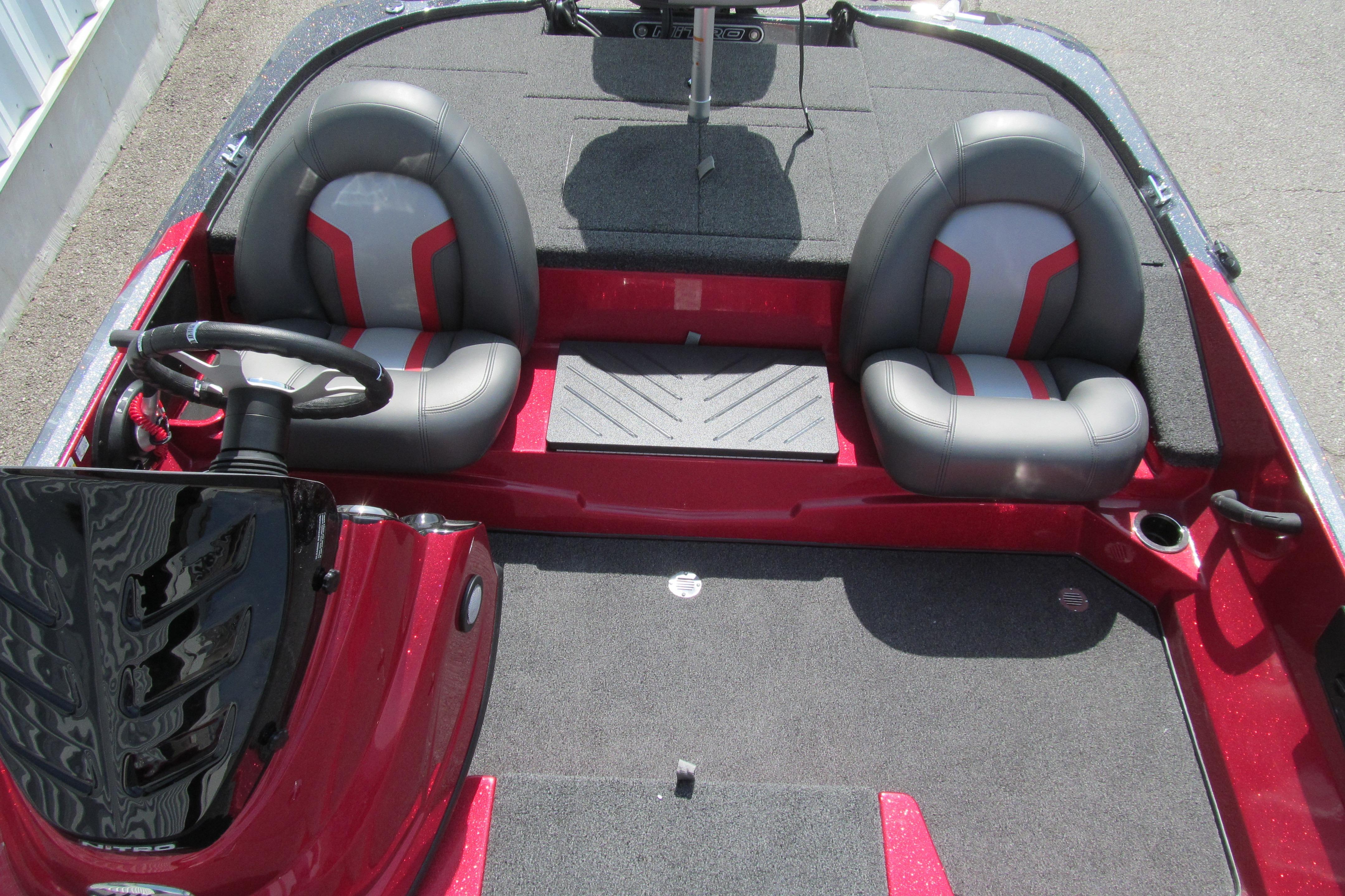 2026 Nitro Z17 boat interior with dual gray and red seats, steering wheel, and carpeted flooring.