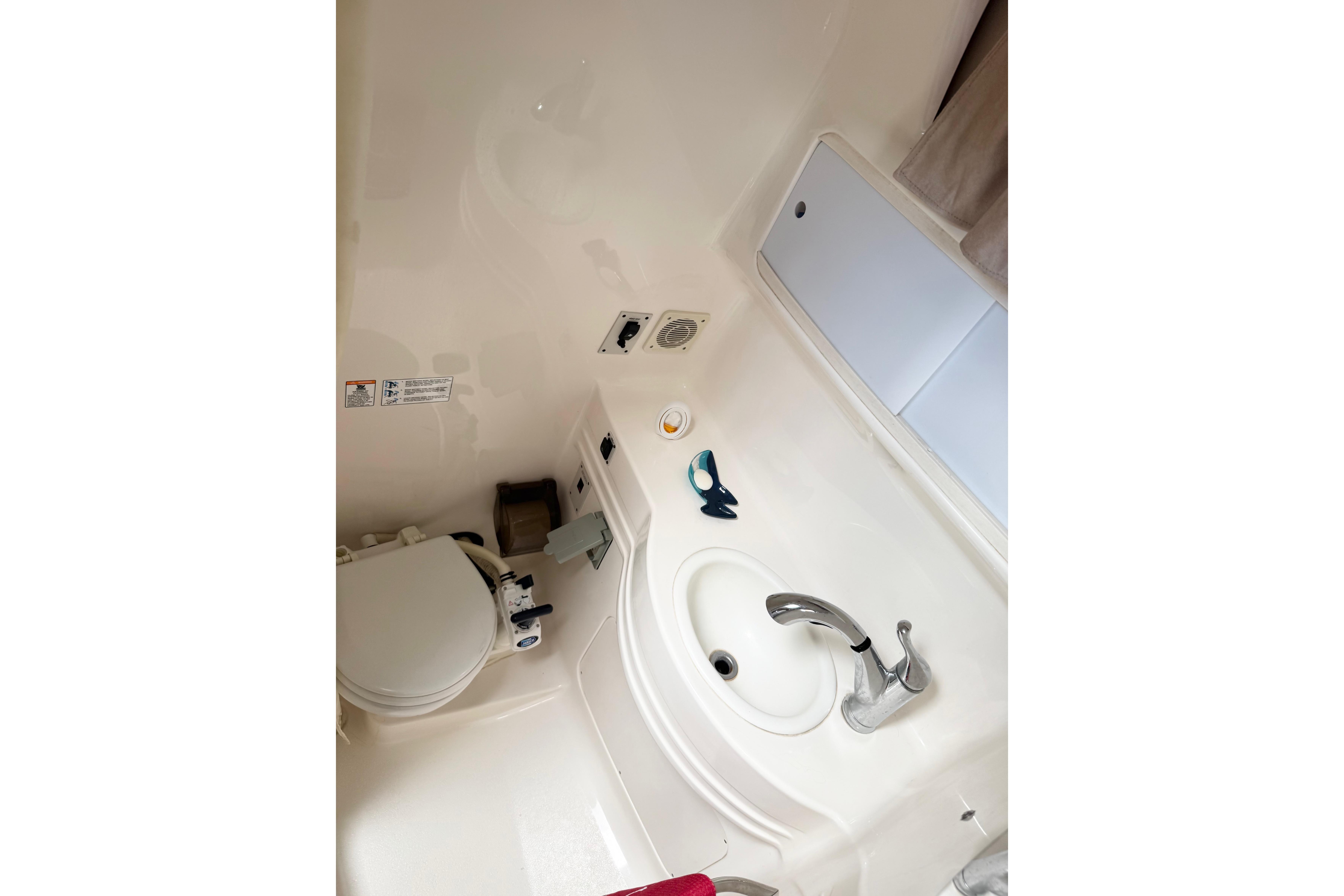 1999 Chaparral Signature 300 boat bathroom with sink, toilet, and storage cabinet.