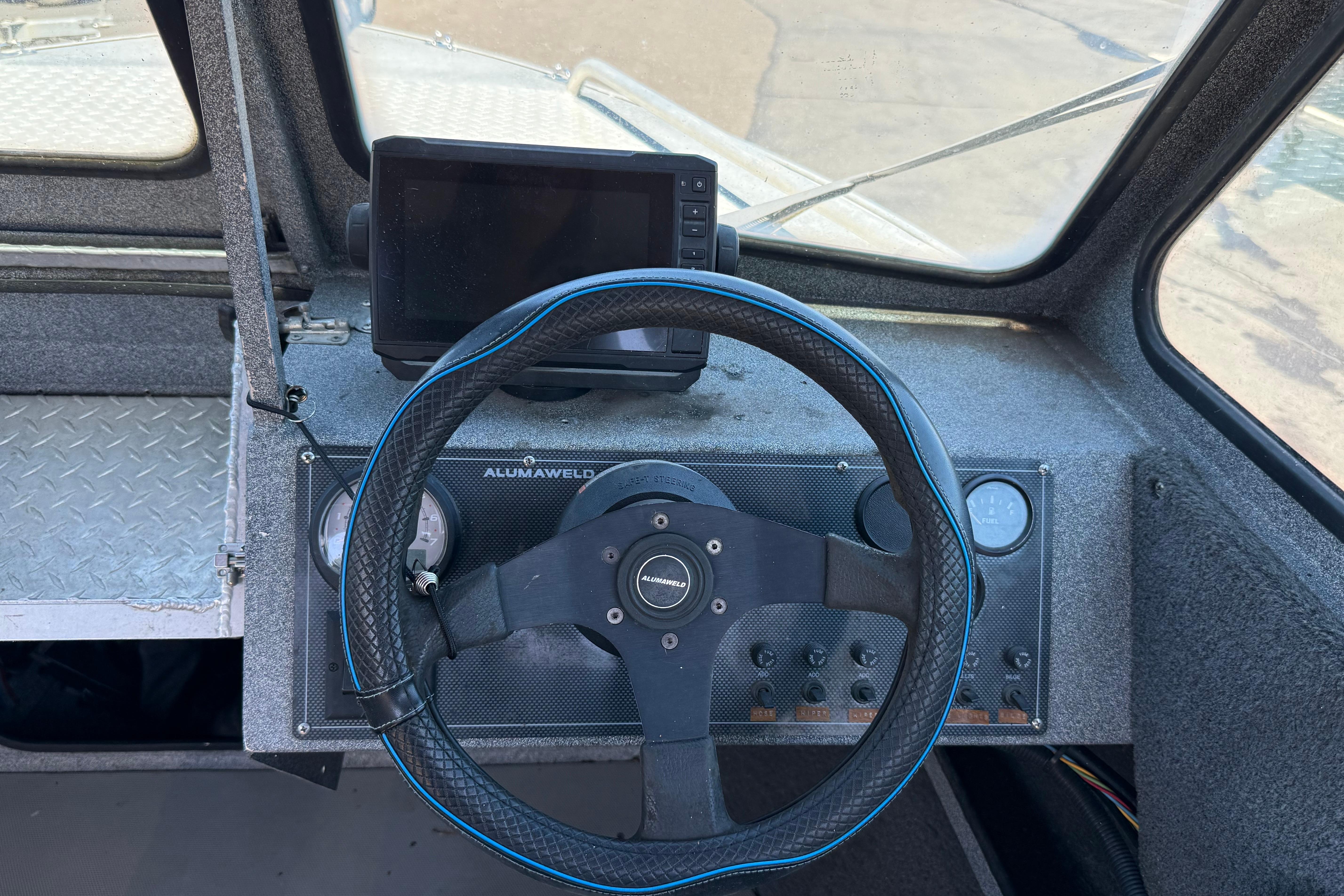 The cockpit of an Alumaweld boat with steering wheel and instruments.