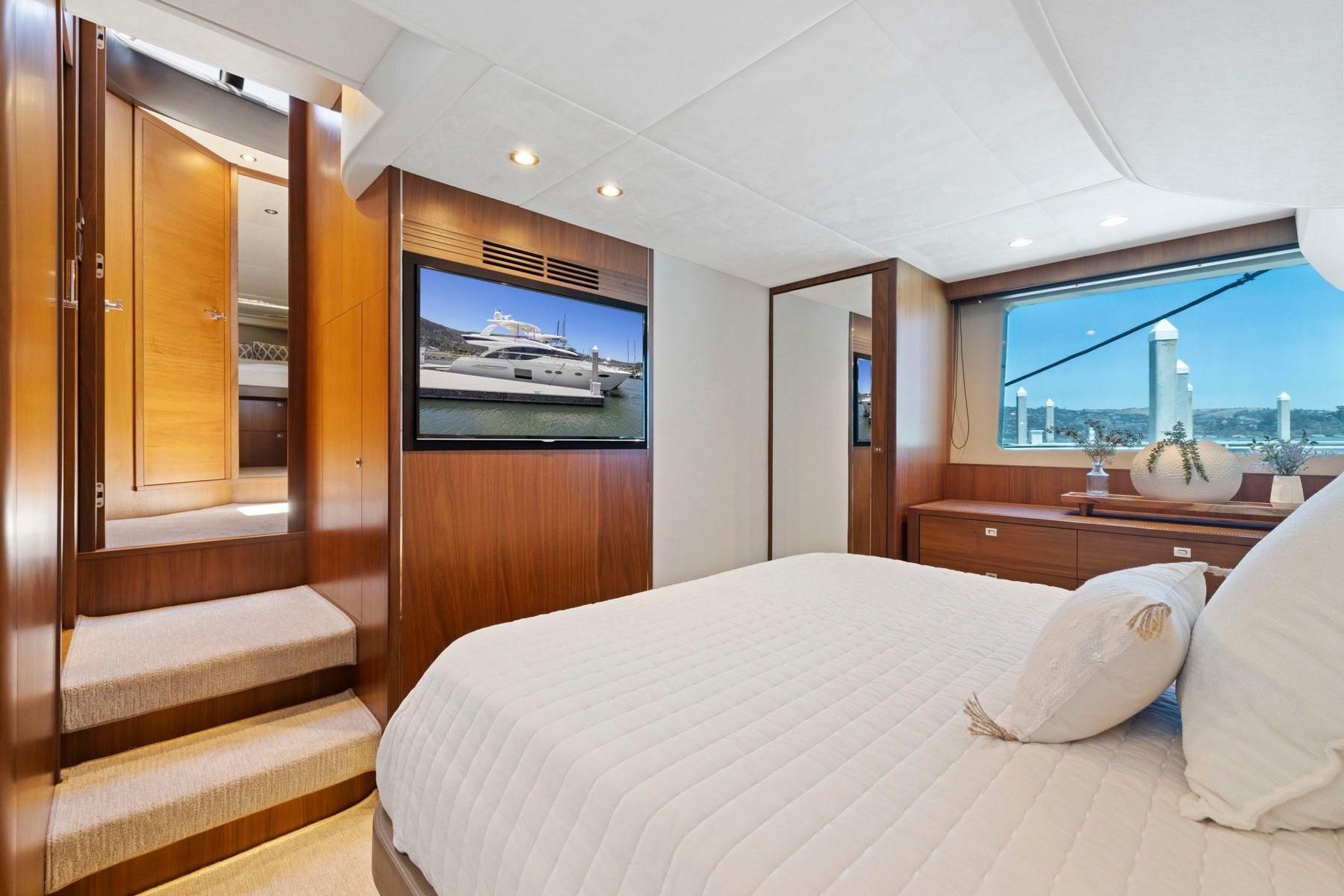Luxurious 2015 Princess 60 Flybridge Motor Yacht bedroom with elegant wood finishes and scenic window view.