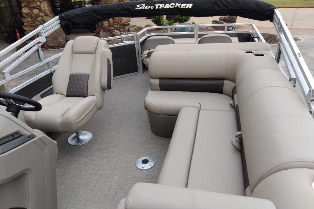 2025 Sun Tracker Fishin' Barge 22 XP3 interior with beige seating and steering console.