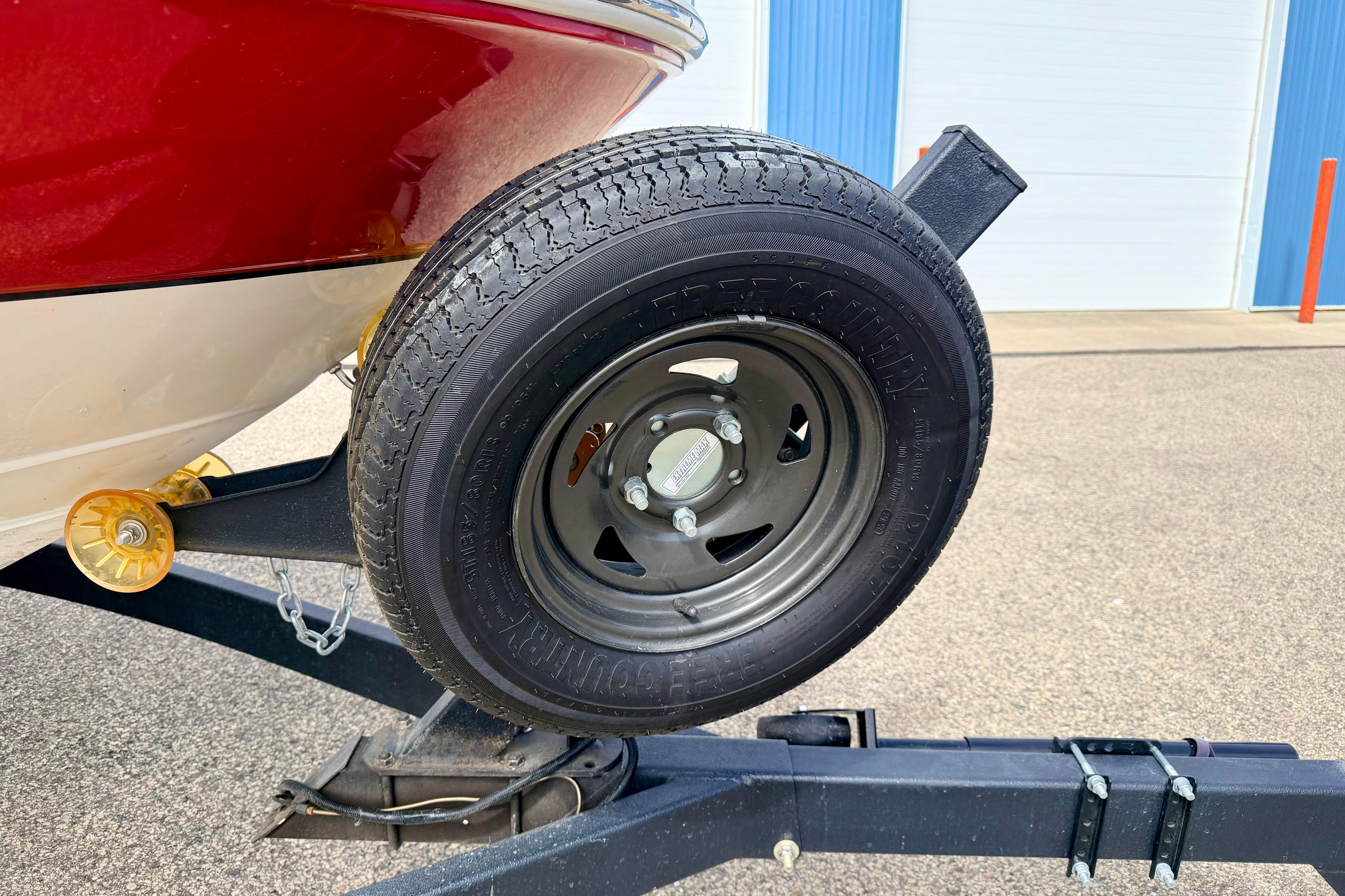 Trailer wheel of a 2003 Sea Ray 200 Sundeck boat, parked on pavement.
