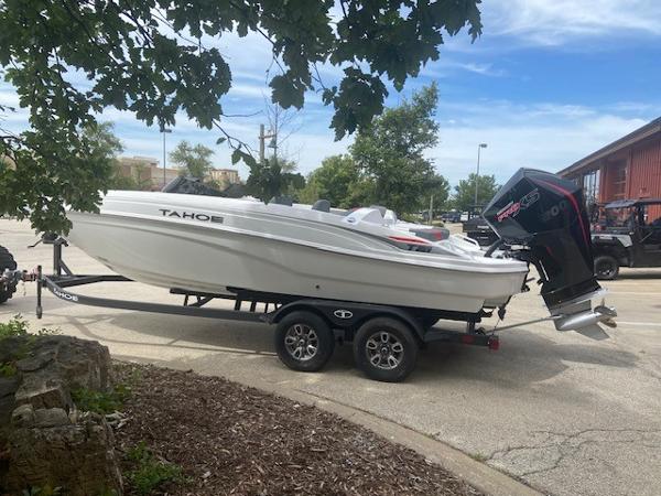 2025 Tahoe T21 boat on trailer, parked outdoors under a tree.