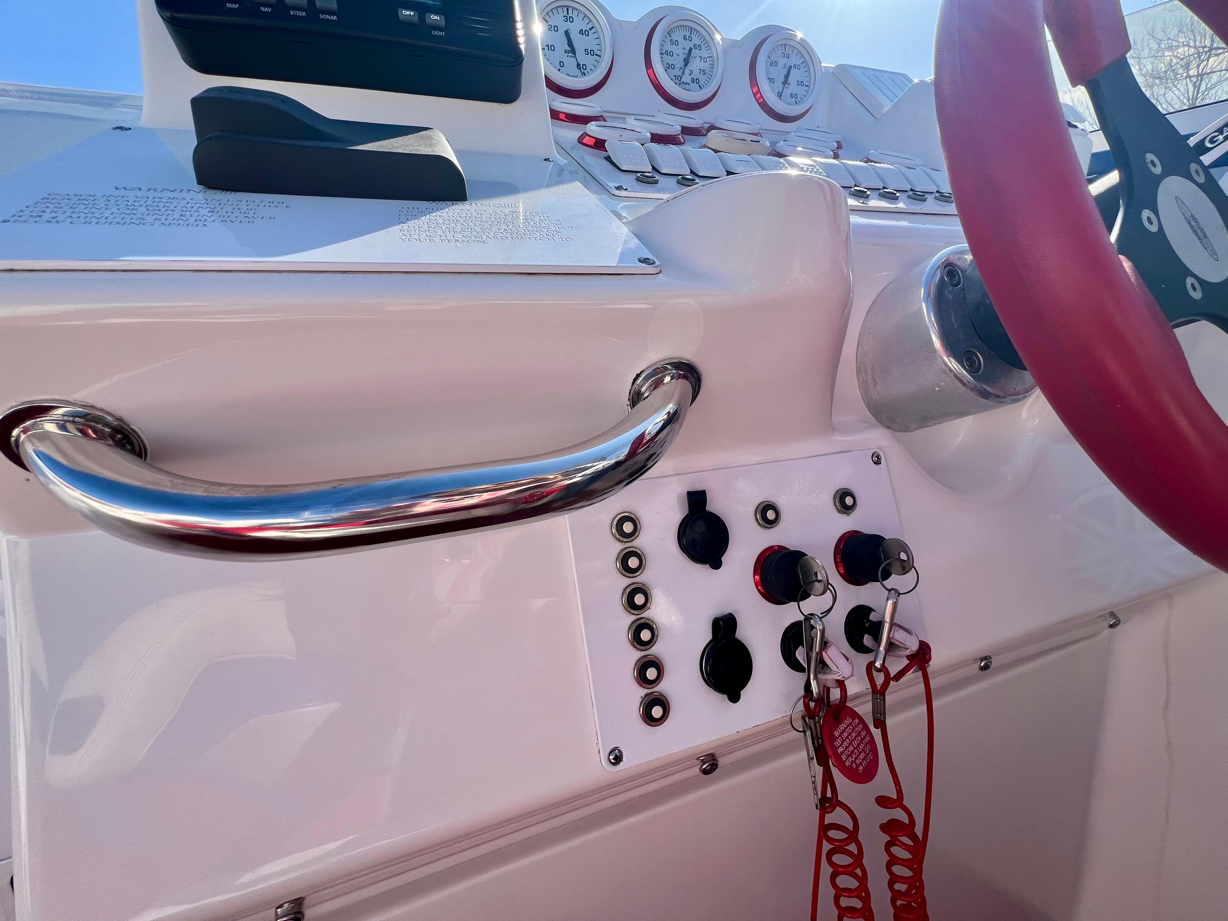 1999 Black Thunder 430 Flat Deck boat dashboard with gauges and controls, featuring a red steering wheel.