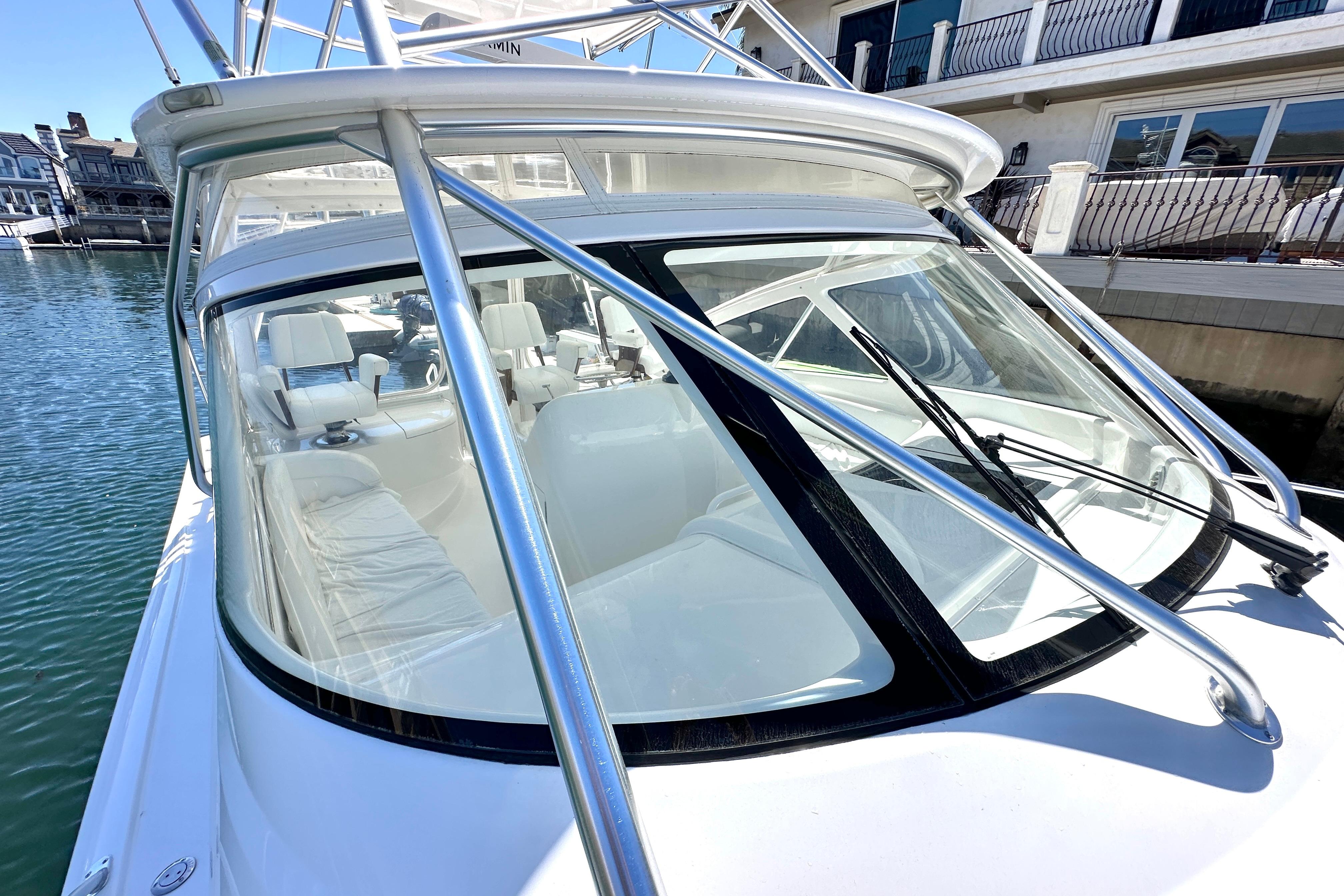 2012 Viking 42 Open yacht with sleek design, docked by waterfront homes.