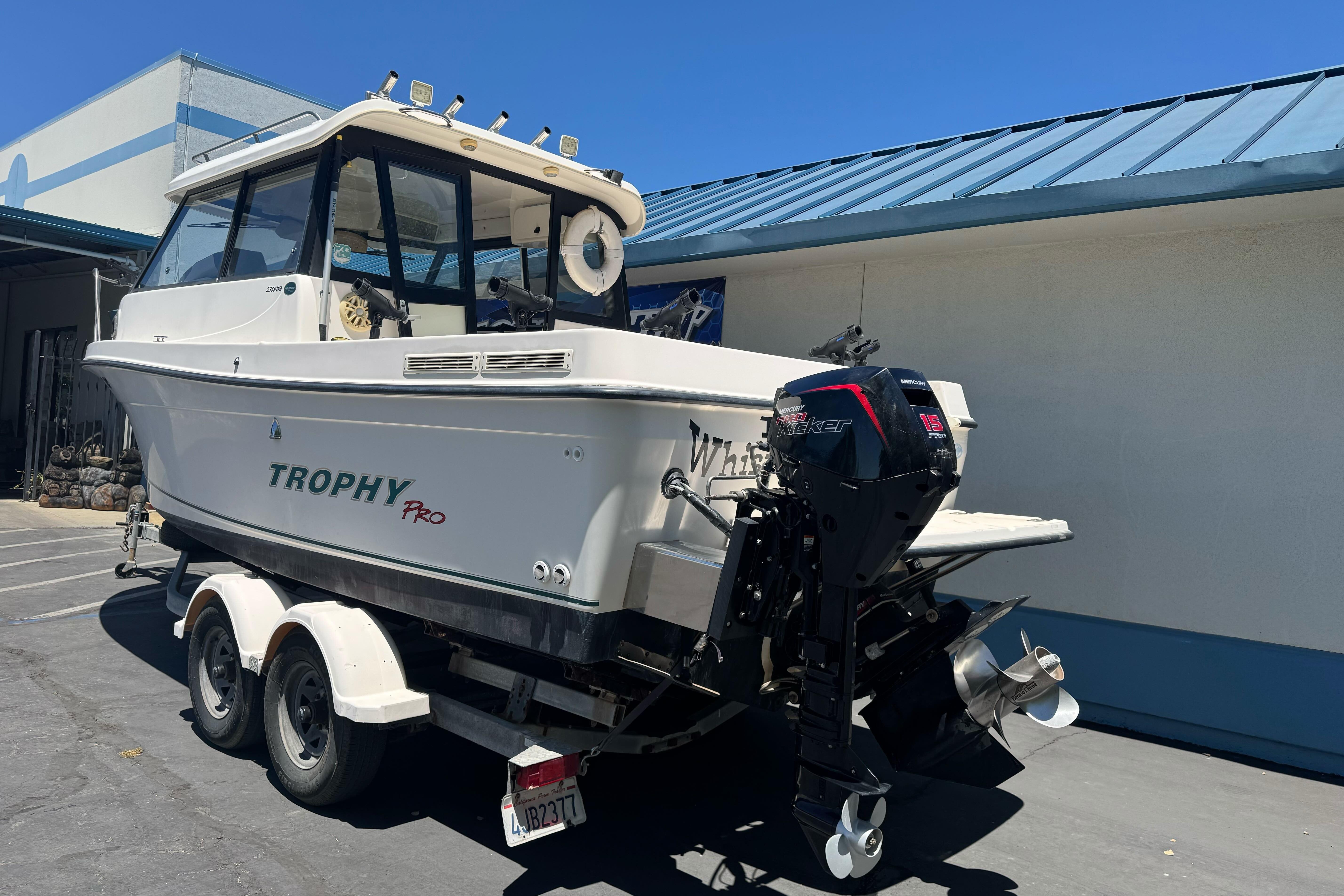 2004 Trophy 2359 WA boat on trailer, parked outdoors, featuring Mercury outboard motor.