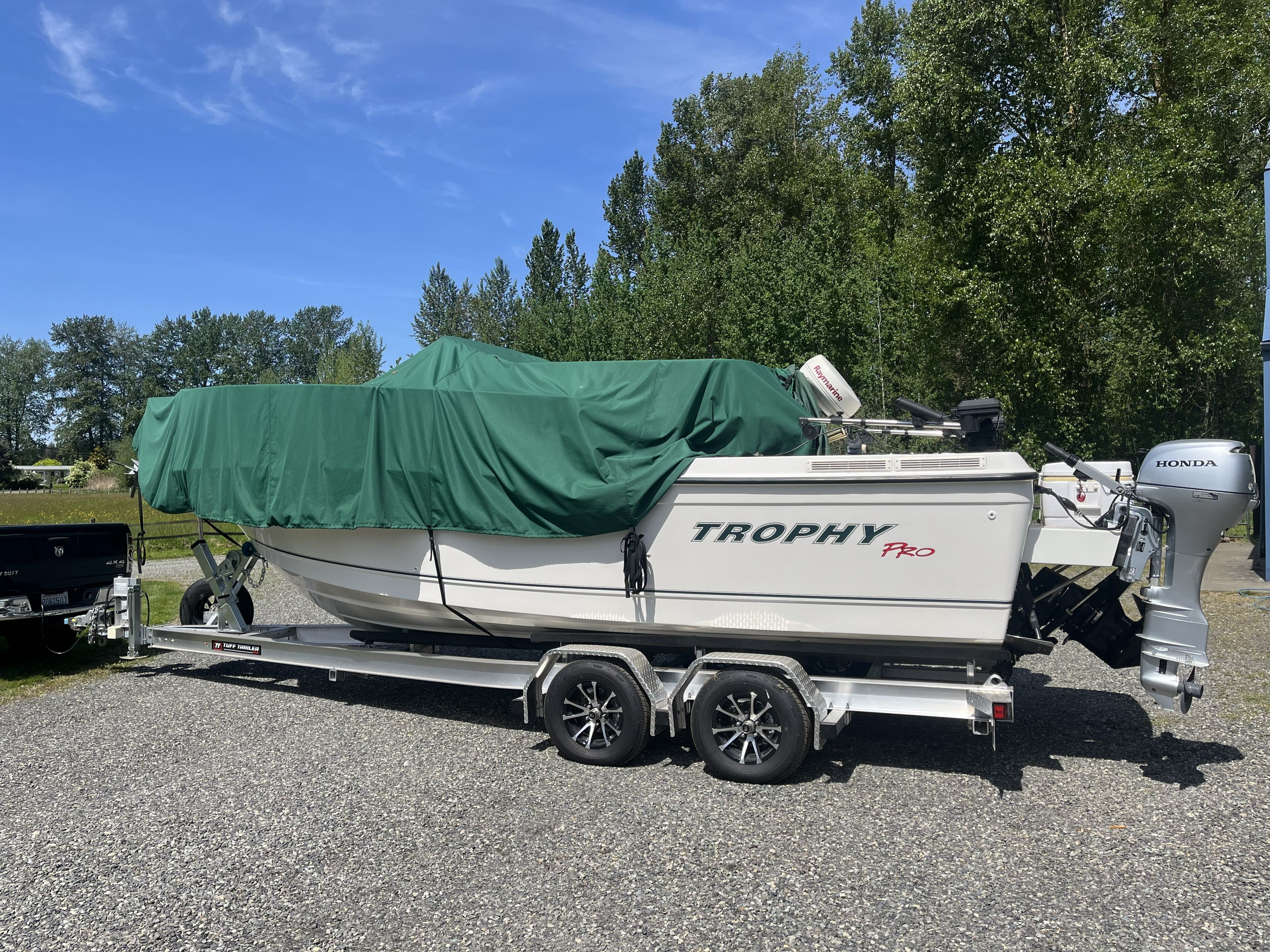 A 2006 Trophy 2352 Walkaround boat on a trailer, covered with a green tarp.