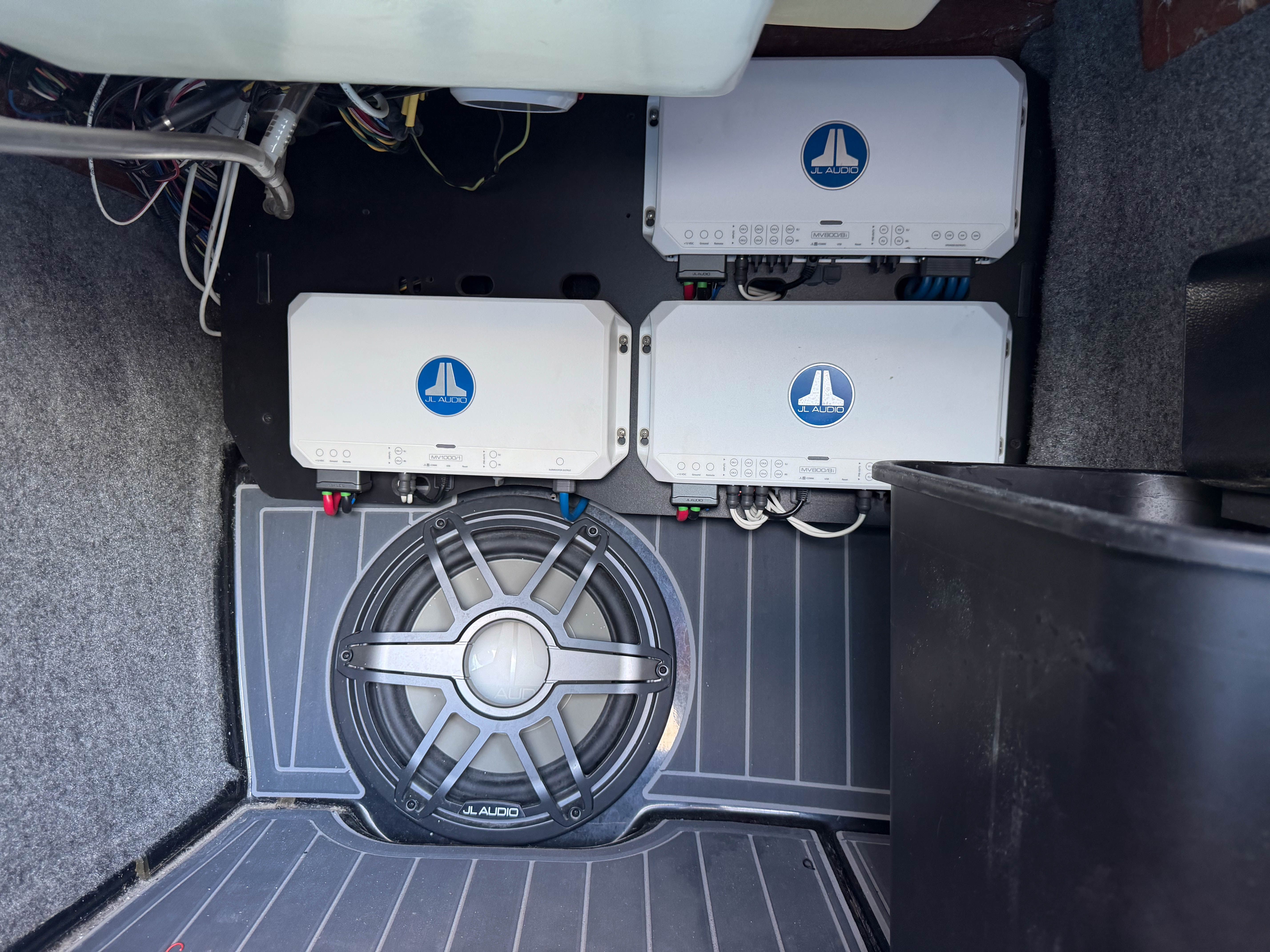 A JL Audio sound system in a boat with amplifiers and subwoofer.