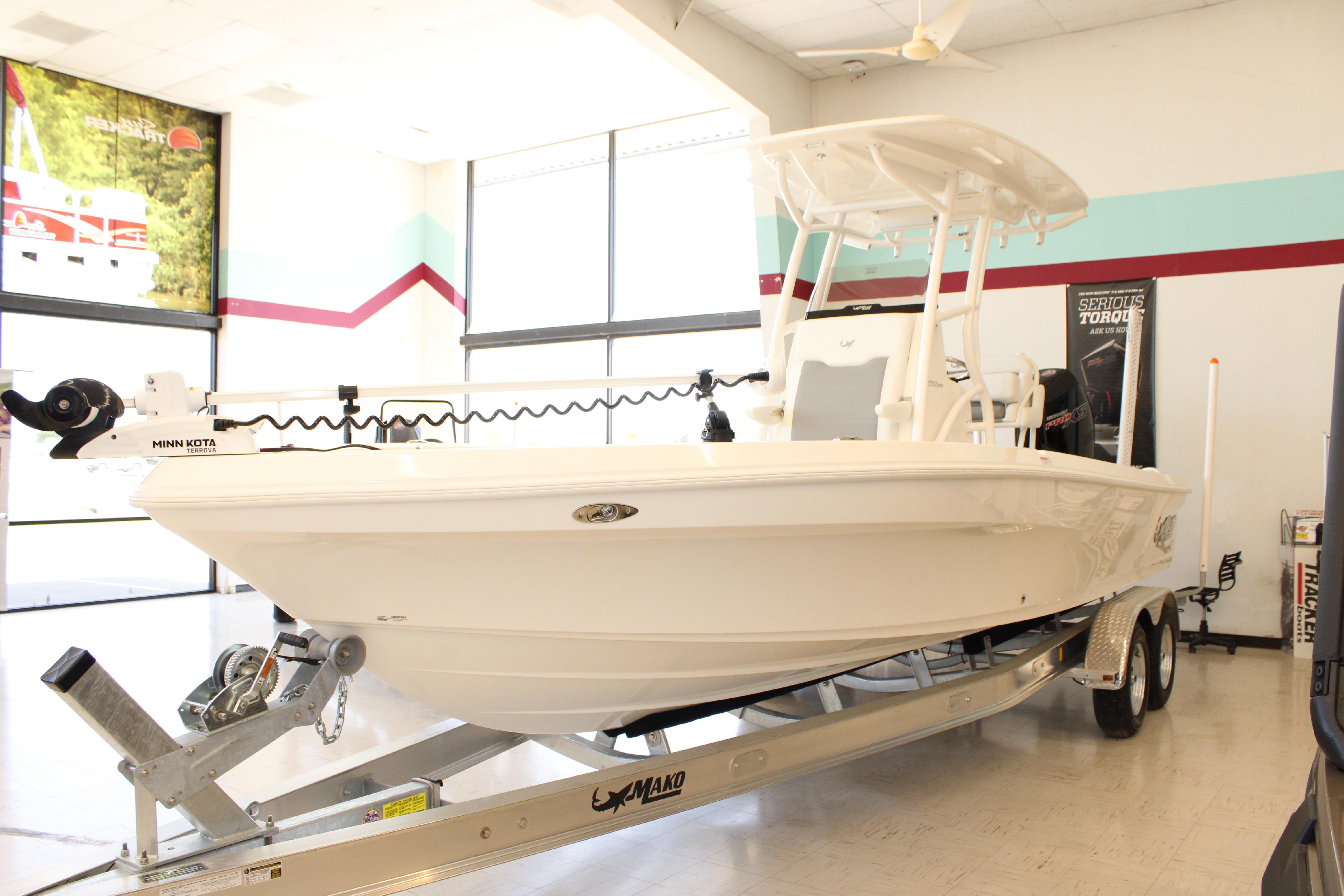 2026 Mako 24 APEX boat on trailer in showroom, featuring Minn Kota trolling motor.