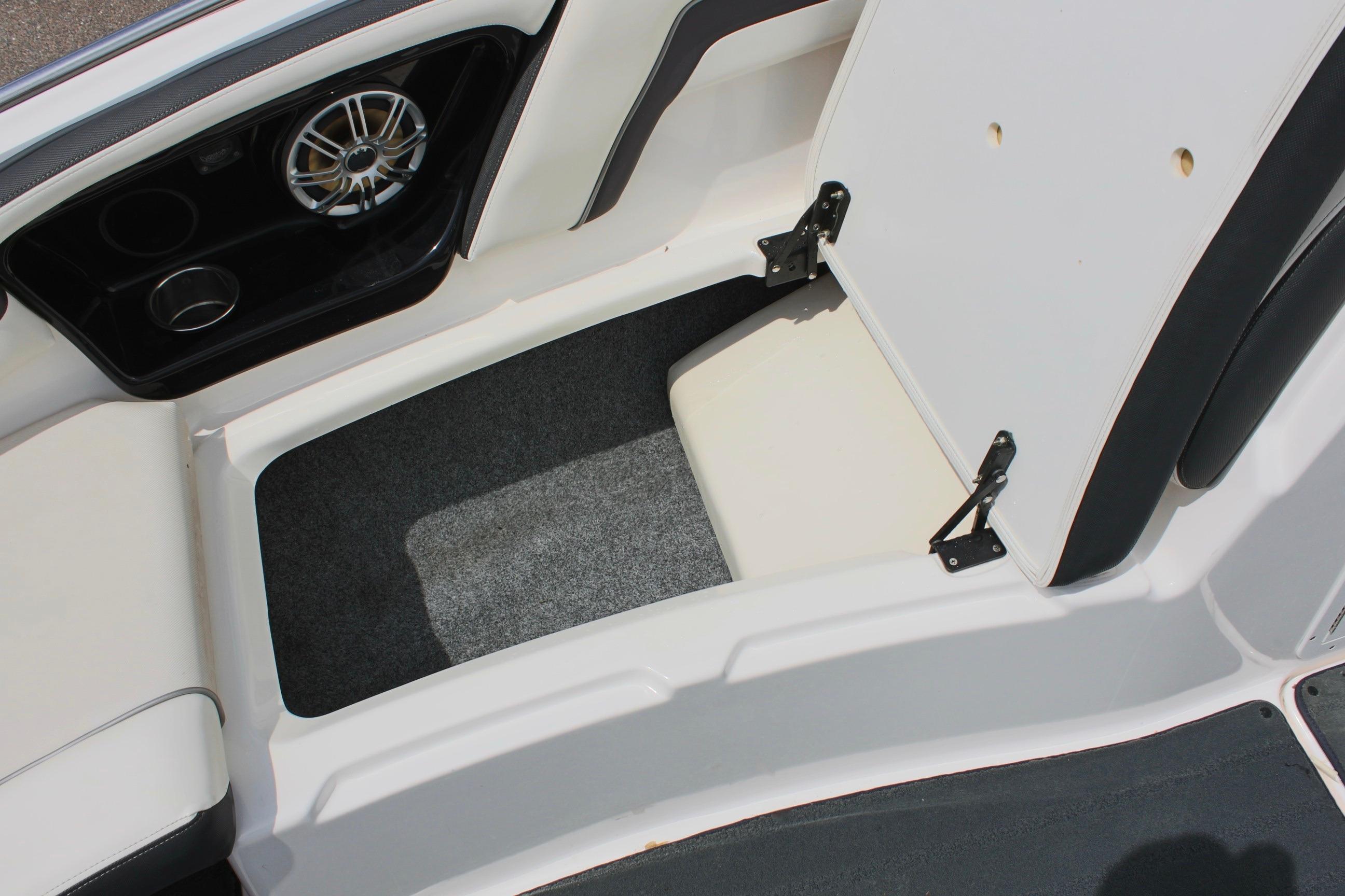 Open storage compartment in 2016 Yamaha Boats 242 Limited S, featuring carpeted interior and speaker.