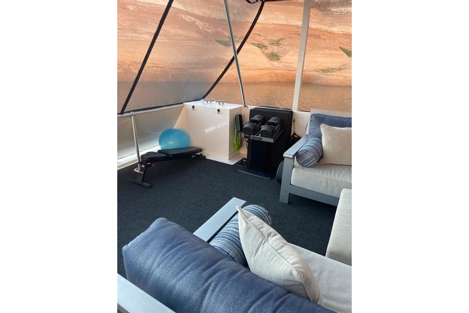 Luxurious seating area on Adonia's 2021 "The Queen Elizabeth" yacht with fitness equipment.