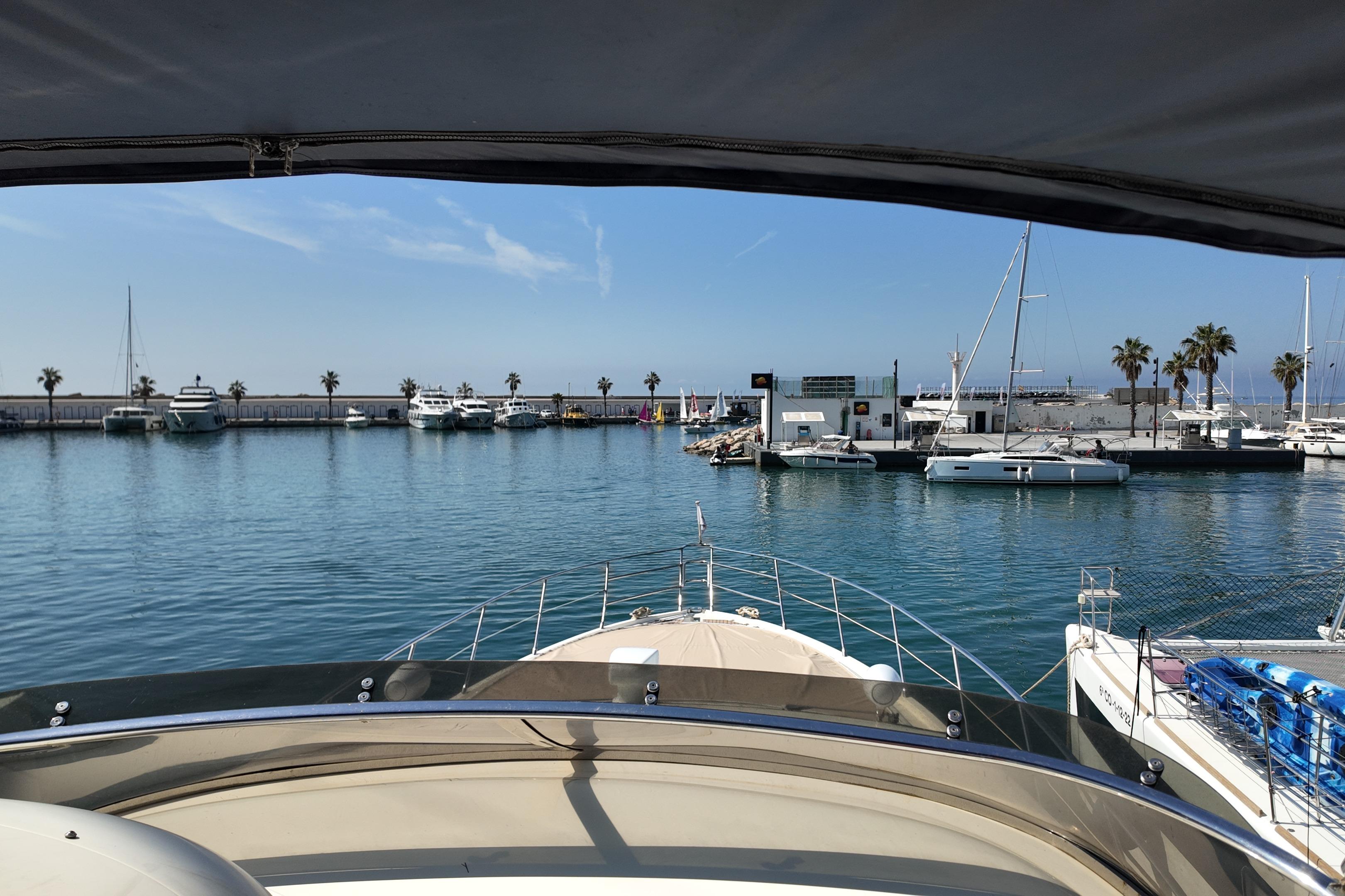 View from 2006 Azimut 68E yacht in a sunny marina with palm trees and boats.