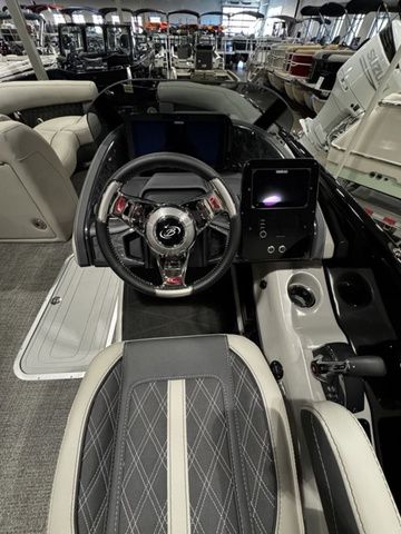 2025 Barletta Boats R23UCA interior with modern steering and dashboard in showroom.