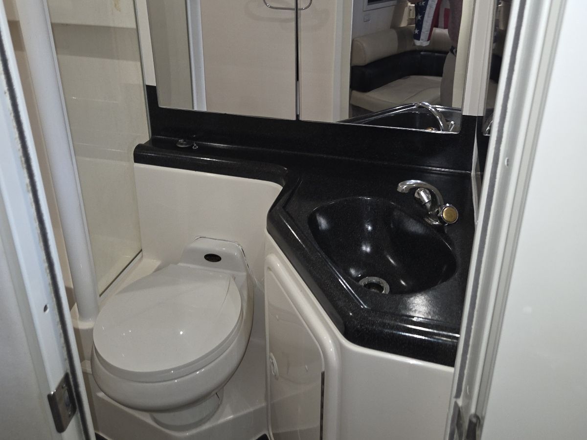 The image shows a boat bathroom with a toilet, sink, and mirror.