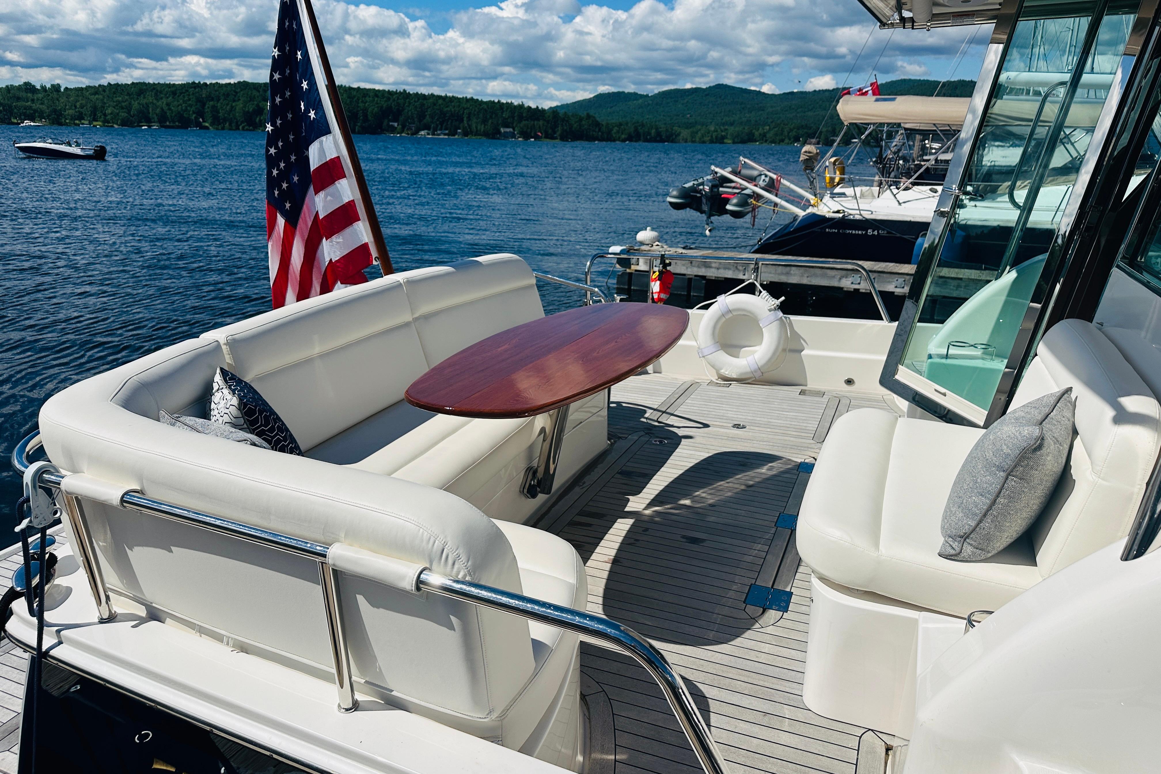 Luxurious 2025 Sabre 48 Salon Express yacht deck with seating, table, and scenic lake view.