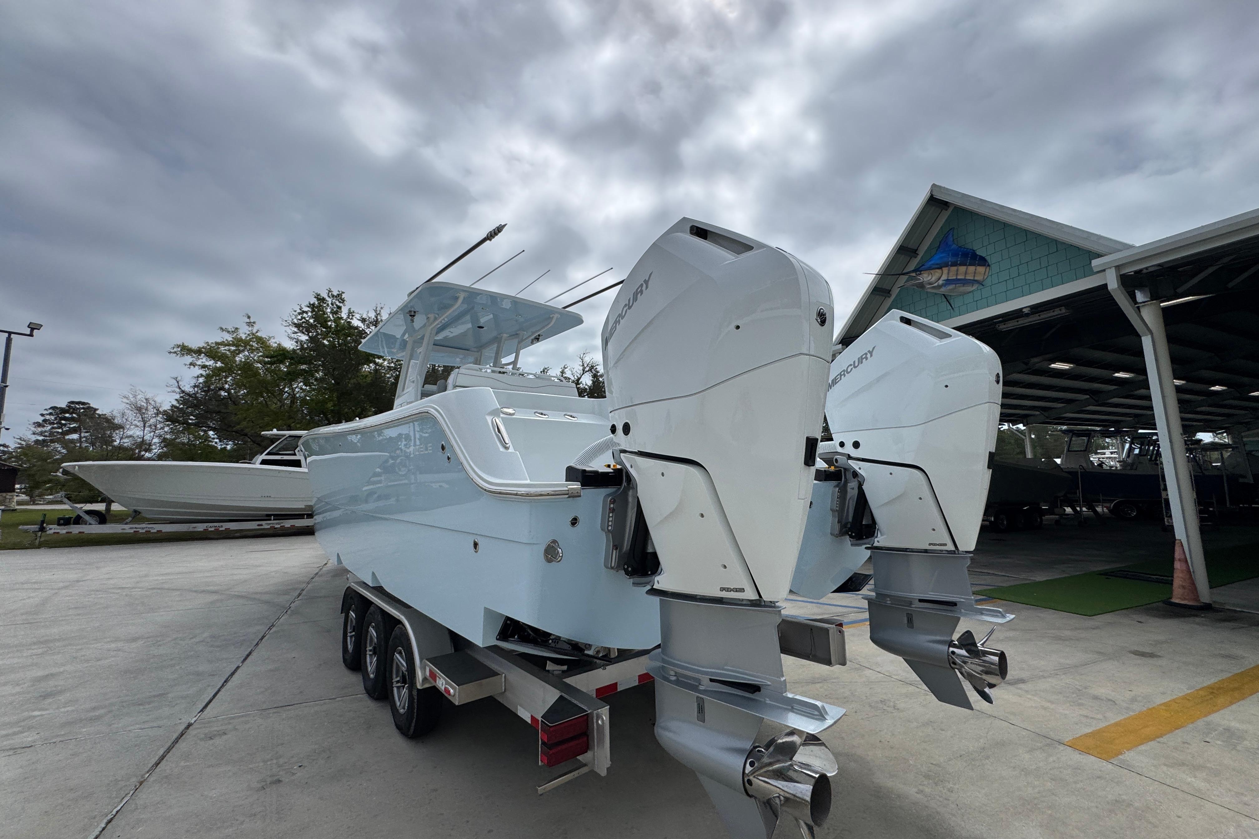 2026 Invincible 33 Catamaran with dual Mercury engines on a trailer, under cloudy skies.