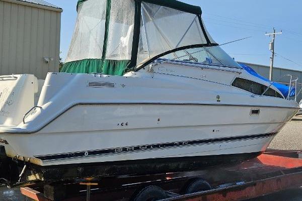 1997 Bayliner 2655 Ciera boat on trailer, featuring a green canopy and sleek design.