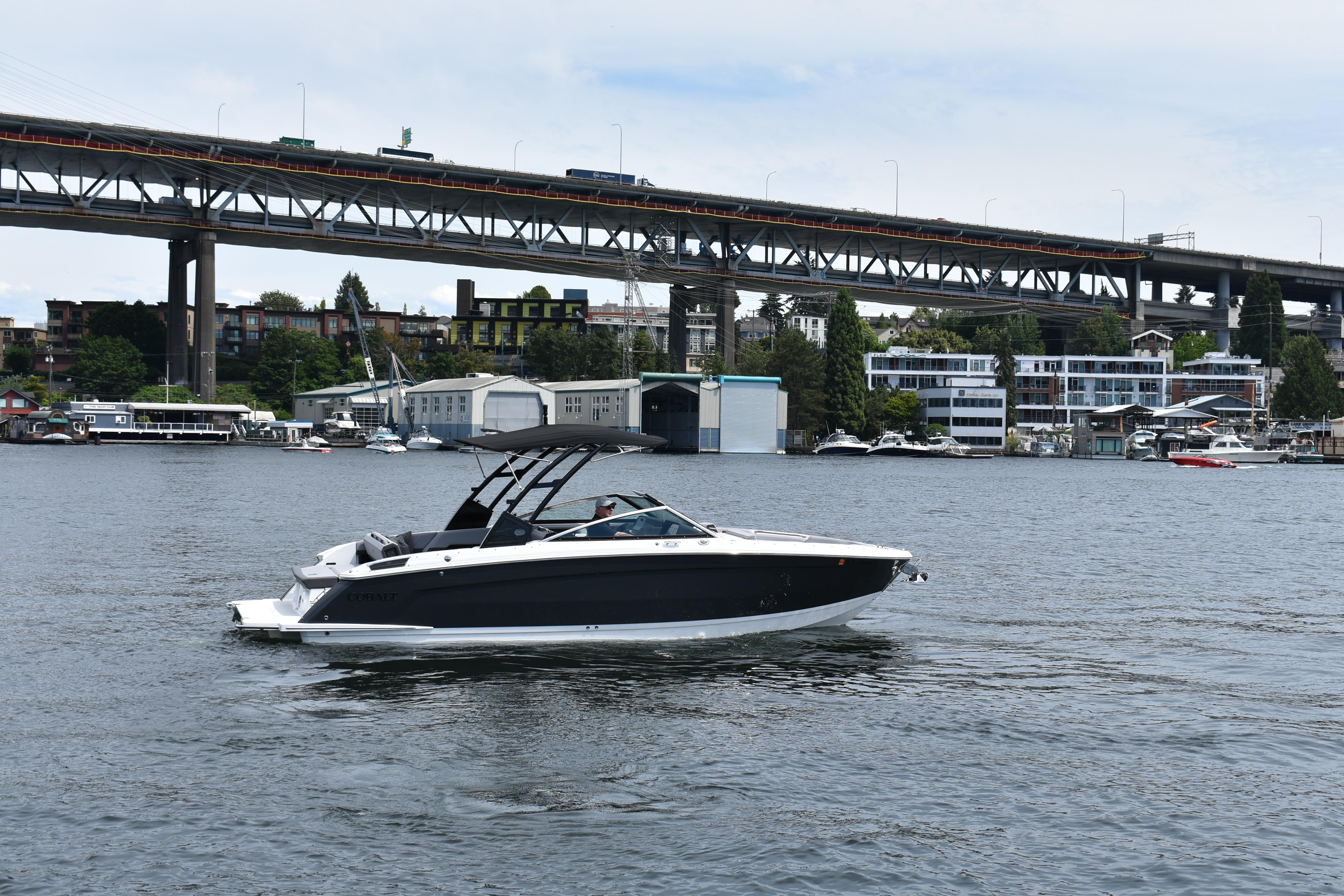 2023 Cobalt R8 boat cruising on a river with a bridge in the background.