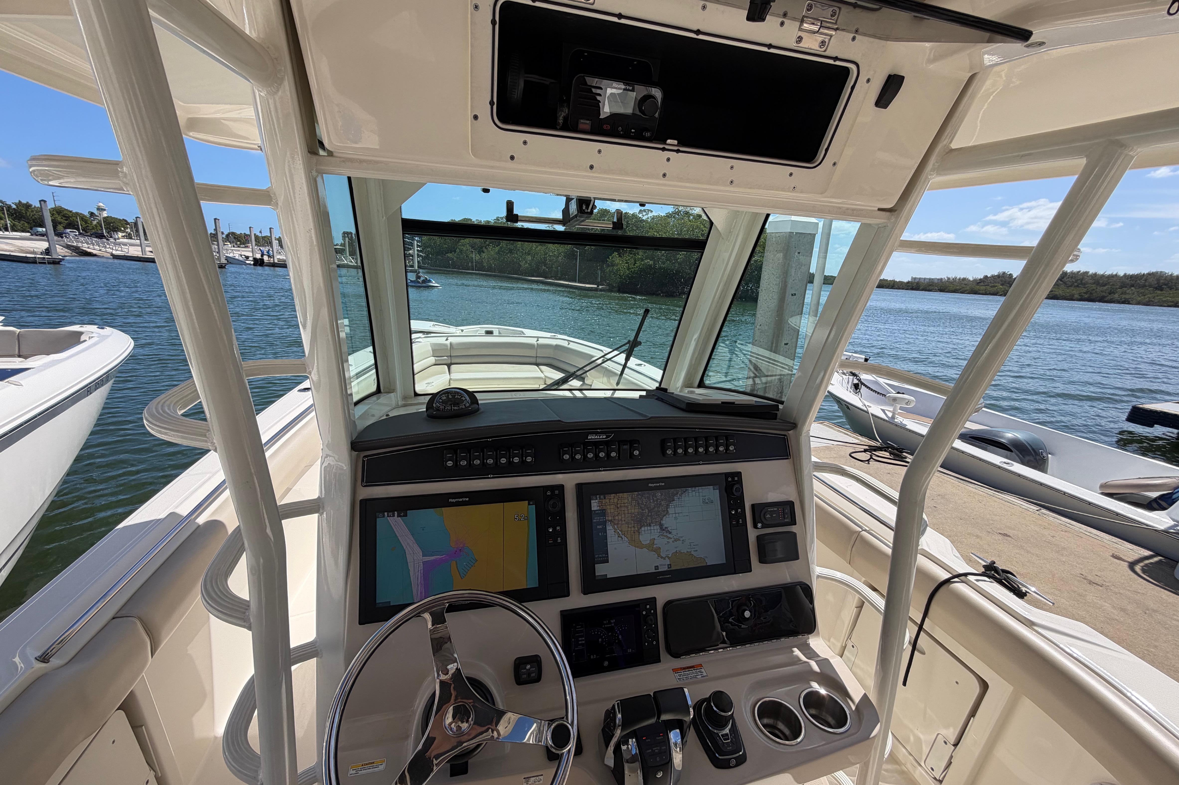 2019 Boston Whaler 330 Outrage helm with navigation screens, docked by the water.
