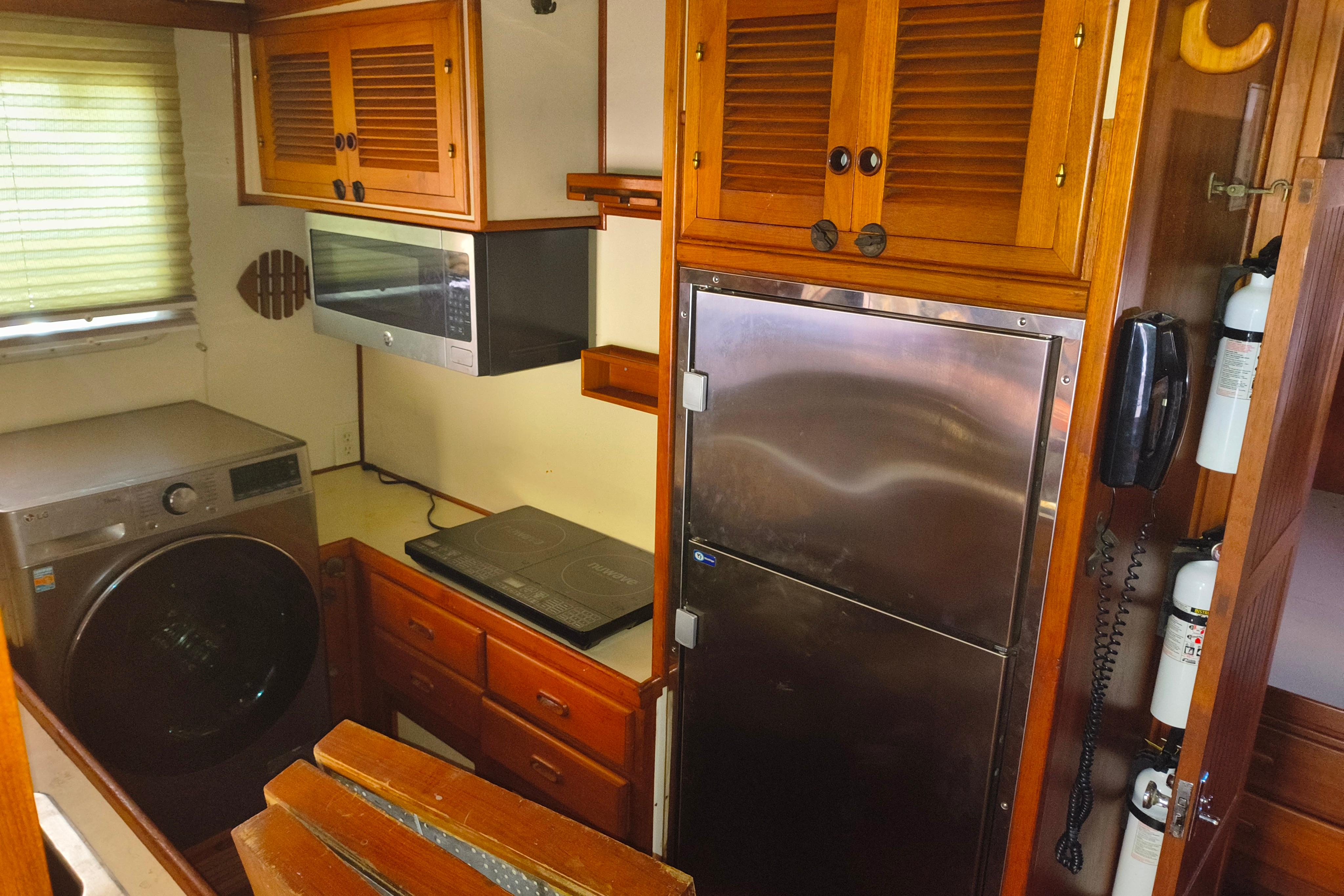 1984 Kadey-Krogen Manatee kitchen with wooden cabinets, stainless steel appliances, and washer.
