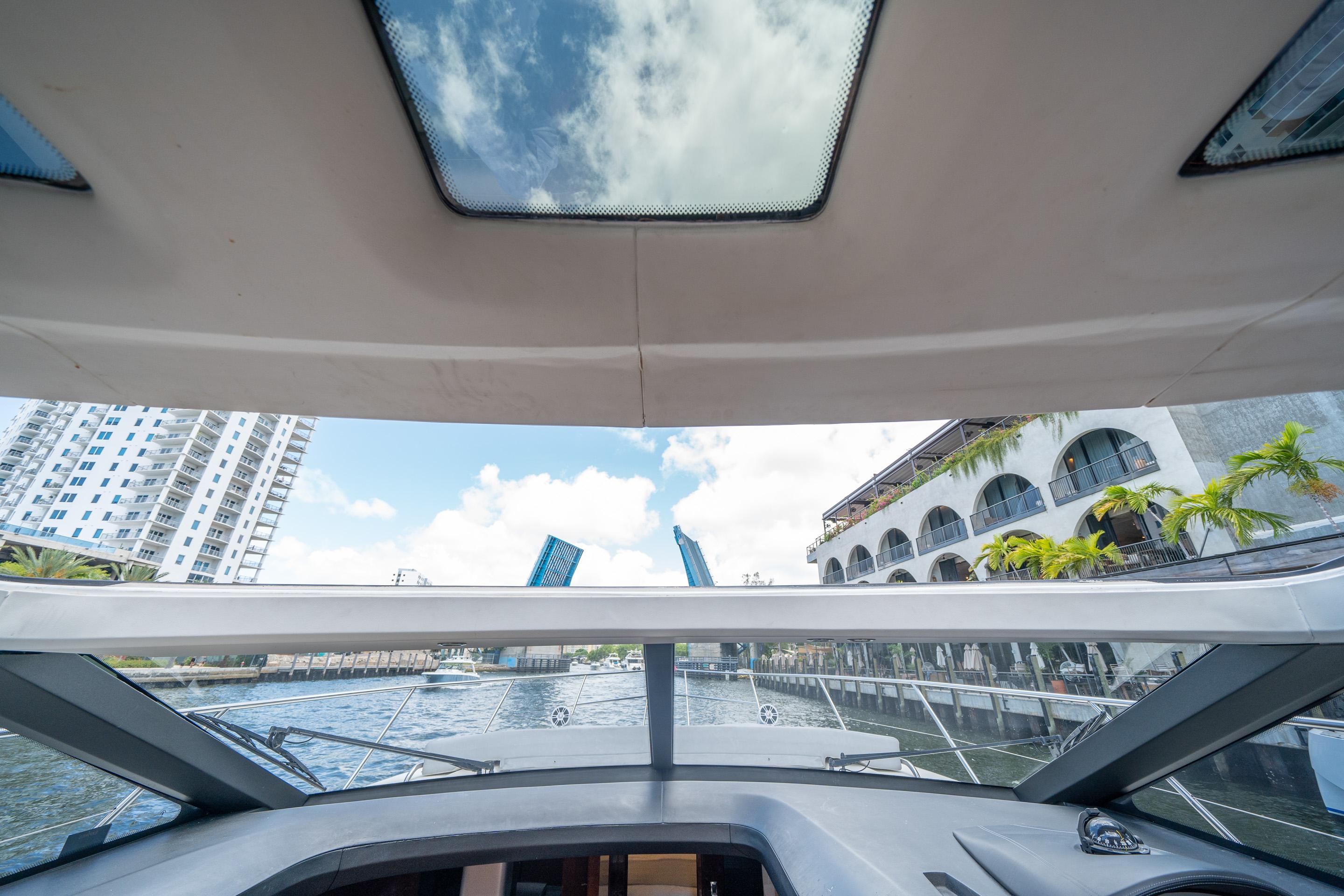 Interior view from 2012 Princess V52 yacht, showcasing open sunroof and waterfront cityscape.