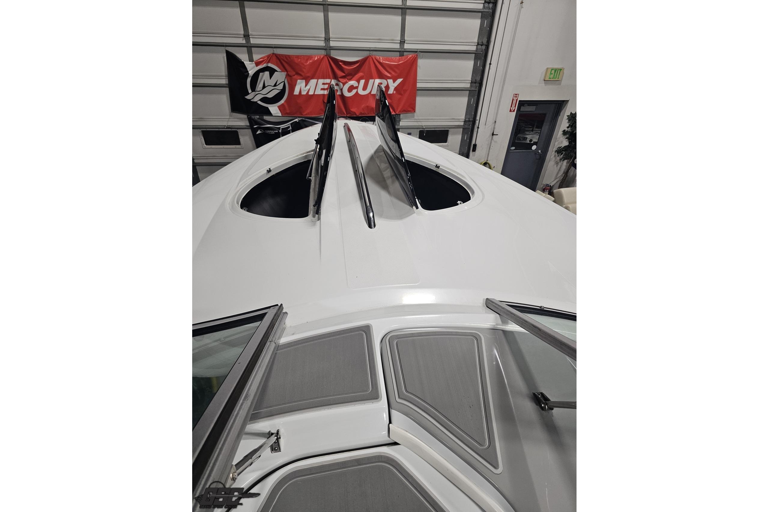2008 Baja 335 Performance boat with open hatches, indoors, Mercury banner visible.