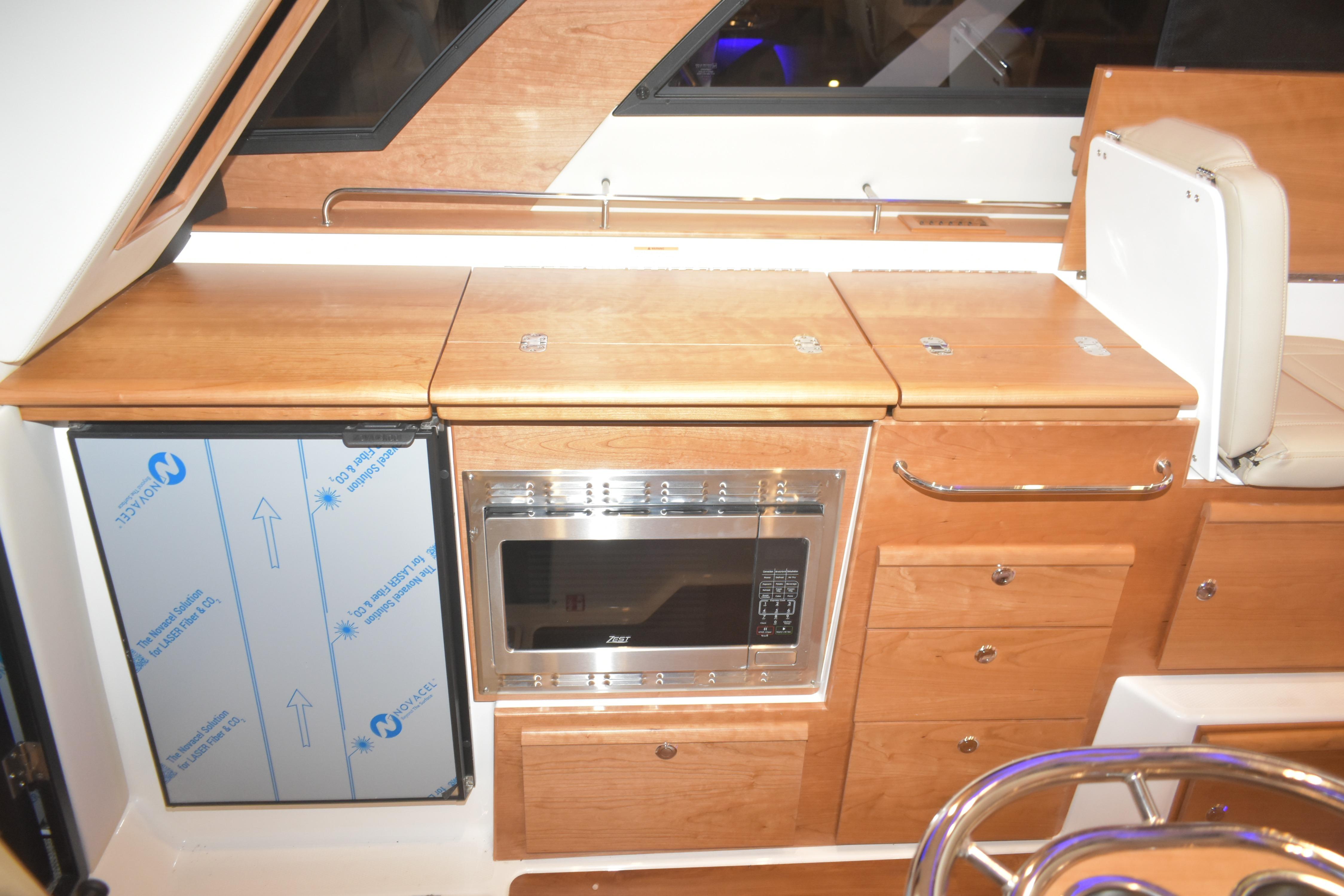 2026 Cutwater C-32 CB interior kitchen with microwave, fridge, and wooden cabinetry.