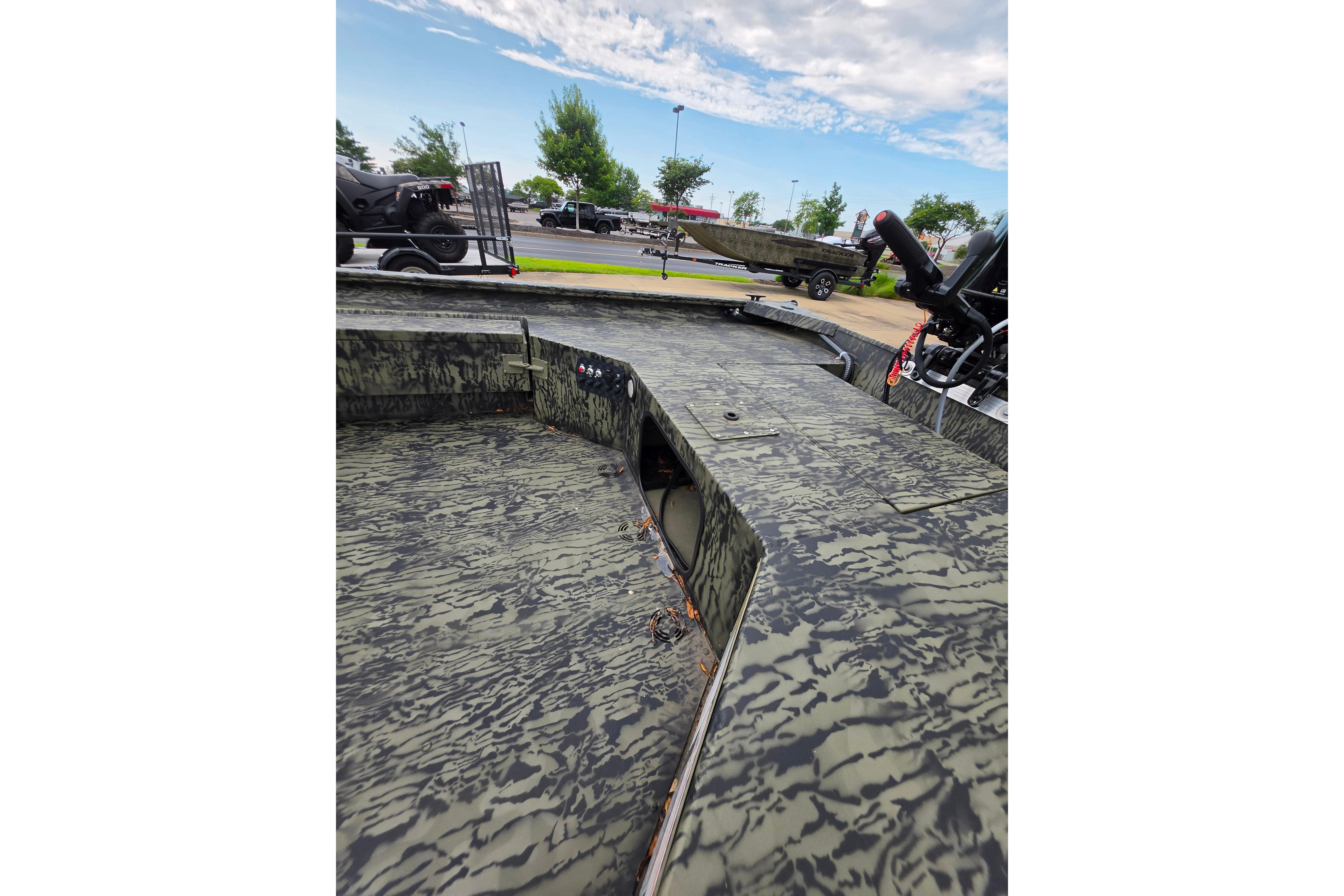 2026 Tracker Grizzly 1654 T Sportsman boat with camouflage design, parked outdoors.
