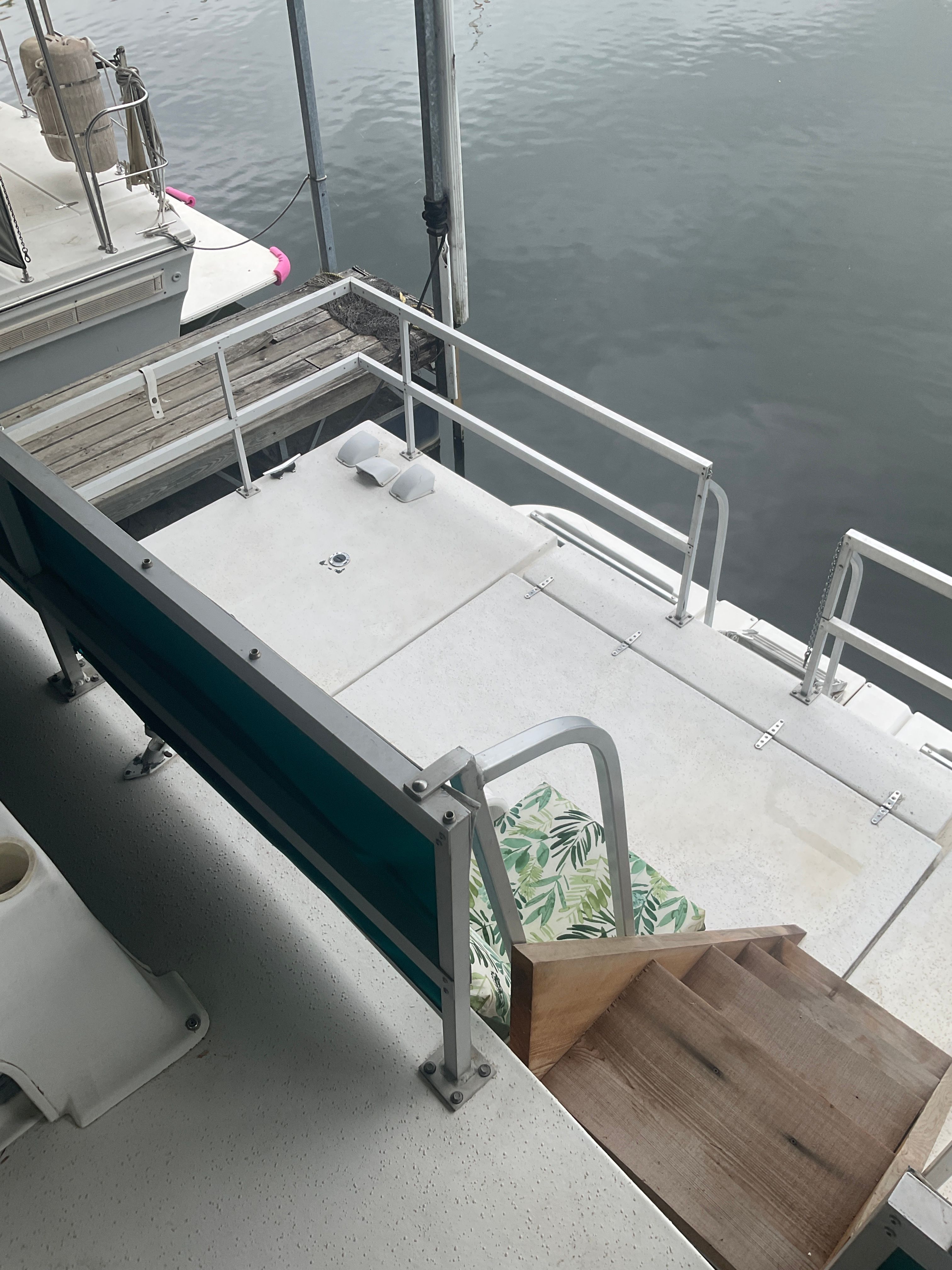 The image shows the stern of a boat with a small platform and stairs. It is docked.