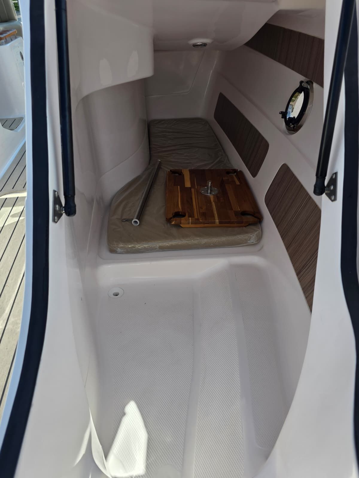 Interior of a 2025 Coral 26 with seating area and porthole.