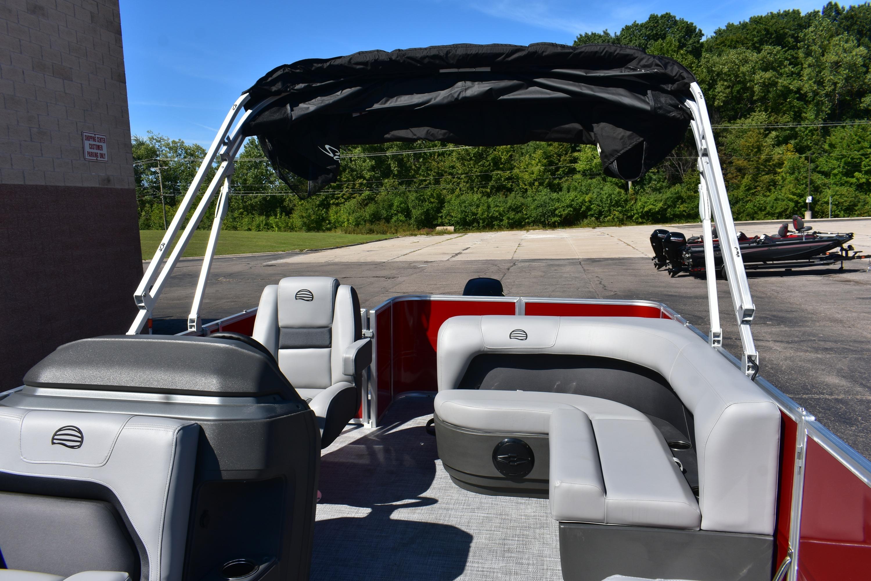 2026 Sun Tracker Party Barge 18 DLX pontoon boat with seating and canopy, parked outdoors.