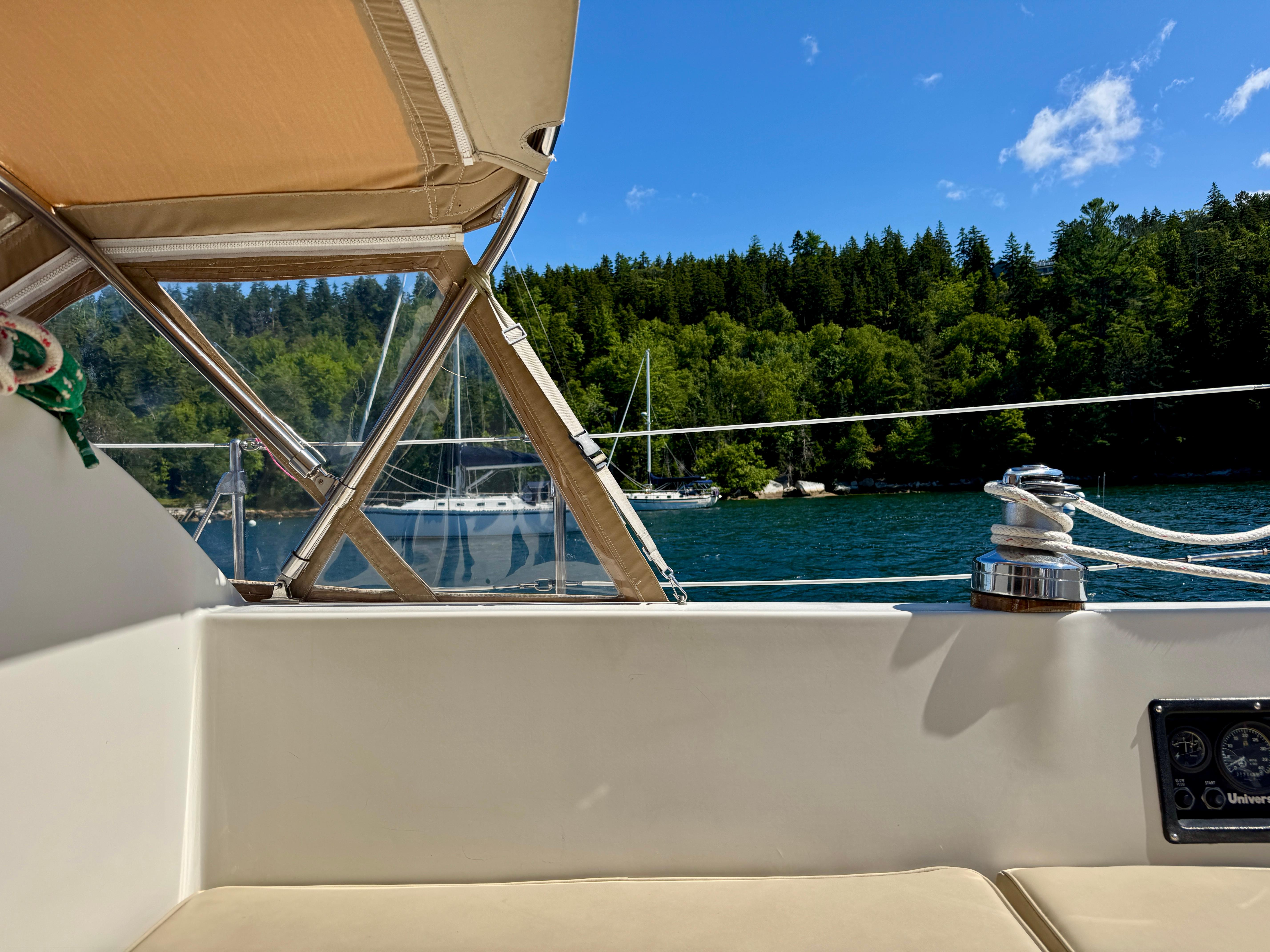 View from a 1989 Nonsuch 30 Ultra sailboat, overlooking serene waters and lush green forest.