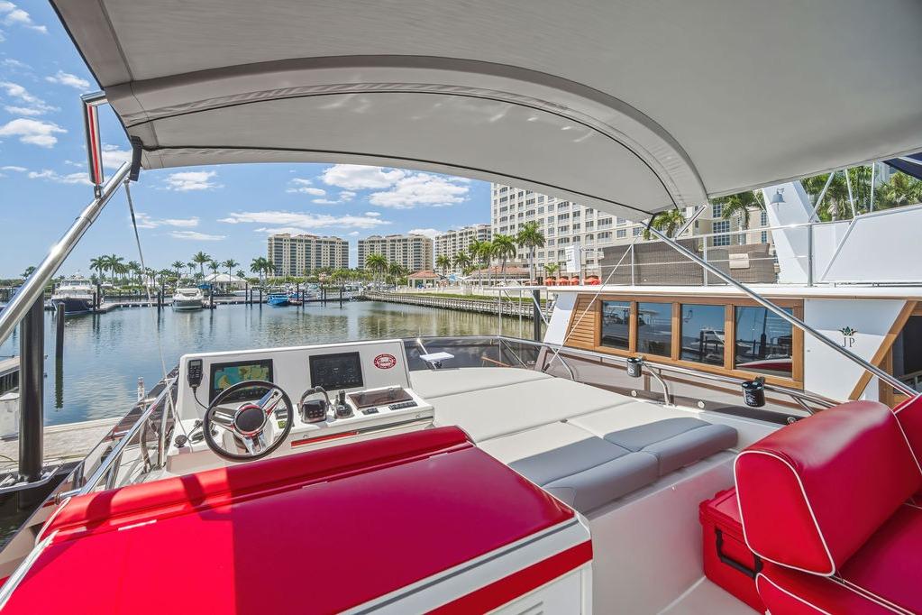 Luxurious 2024 Prestige 520 yacht interior with red seating, docked at a scenic marina.
