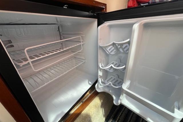 Open refrigerator inside a 2003 Sea Ray 260 Sundancer boat, showing empty shelves and door storage.