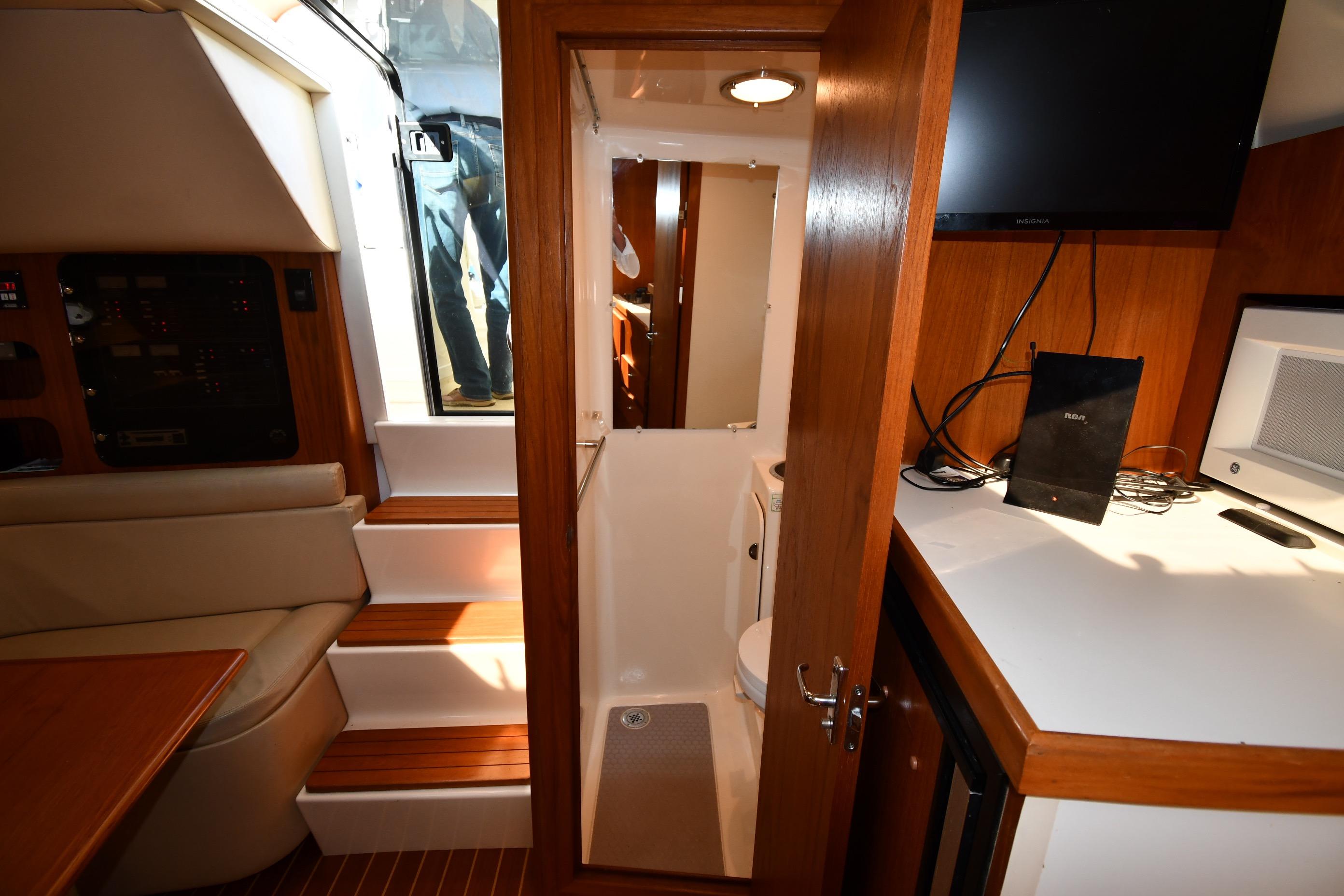 Interior of 1998 Tiara Yachts 3100 Open, featuring cabin seating, steps, and compact bathroom.