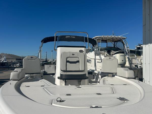 2025 Sea Pro 210 Bay boat with seating and storage, docked under clear blue sky.